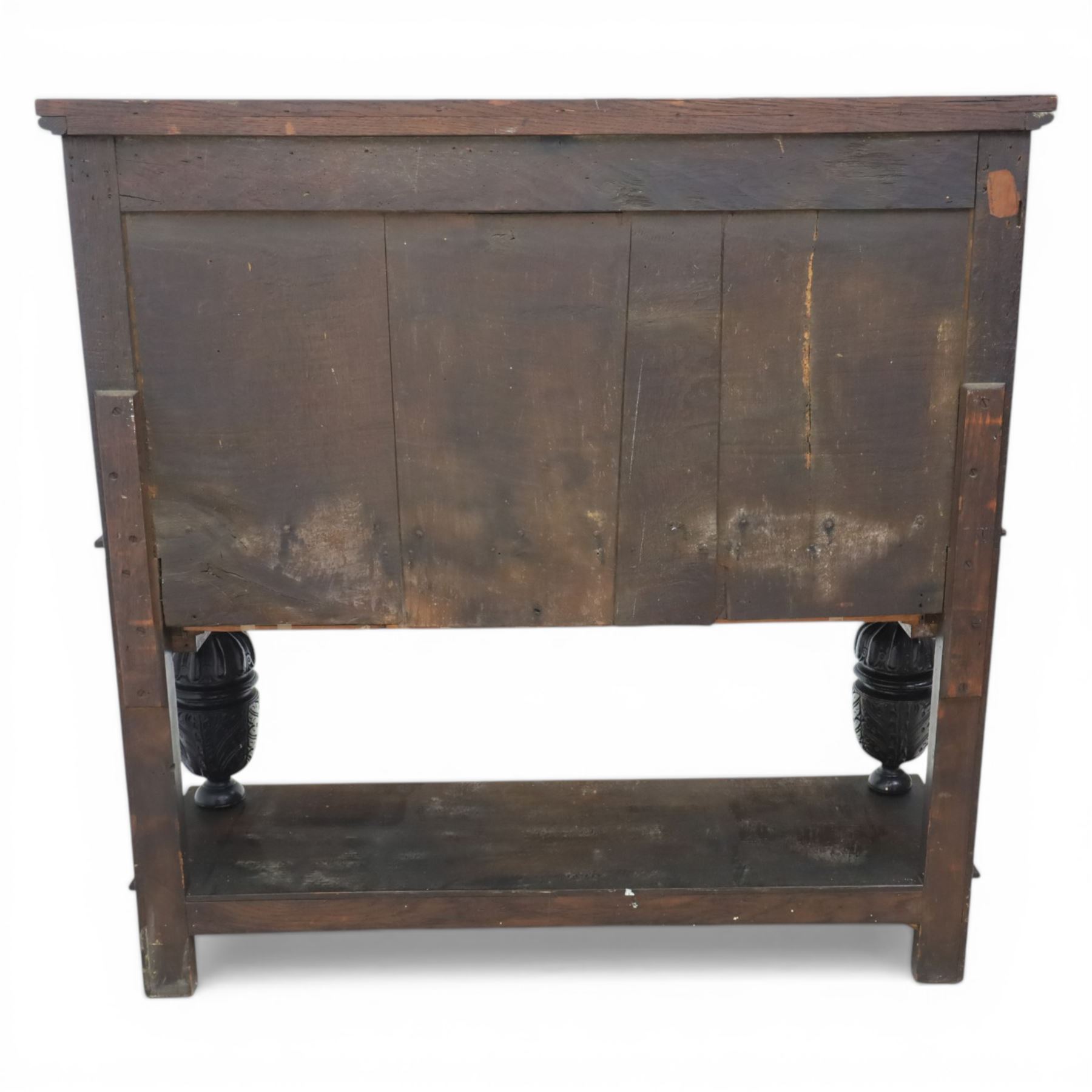 Jacobean revival oak side cabinet, rectangular top above carved frieze of stylised foliage and lunettes, fitted with a central cupboard doors with applied carved panels, above a frieze drawer, supported on turned and carved vase-shaped supports, united by stretcher tier and lower shelf