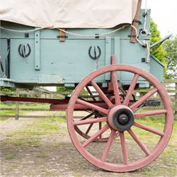 Western Covered Chuck Wagon

A large four wheeled covered wagon of timber construction, painted pale green with red painted wooden spoked wheels and a cream canvas tilt over an arched frame. The wagon has a traditional box body with covered rear compartment, front driving position, underbody turntable steering and iron fittings throughout. Fitted with external equipment details including a side mounted barrel, lidded storage chest, rope tie downs, horseshoe fittings and rear storage box.

Features

• Pale green painted timber body
• Cream canvas tilt over arched frame
• Covered rear compartment
• Front driving position
• Side mounted barrel
• External lidded storage chest
• Rear storage box
• Wooden spoked wheels
• Iron tyres
• Underbody turntable steering
• Rope tie downs
• Horseshoe fittings
• Iron hardware and brackets
• Brass restoration plaque to rear

Dimensions:
Overall length: 335 cm
Width: 170 cm
Height: 275 cm

Wheel Diameters:
Front wheels: 92 cm
Rear wheels: 112 cm

Seating:
Driver: 1
Passenger: Rear covered compartment