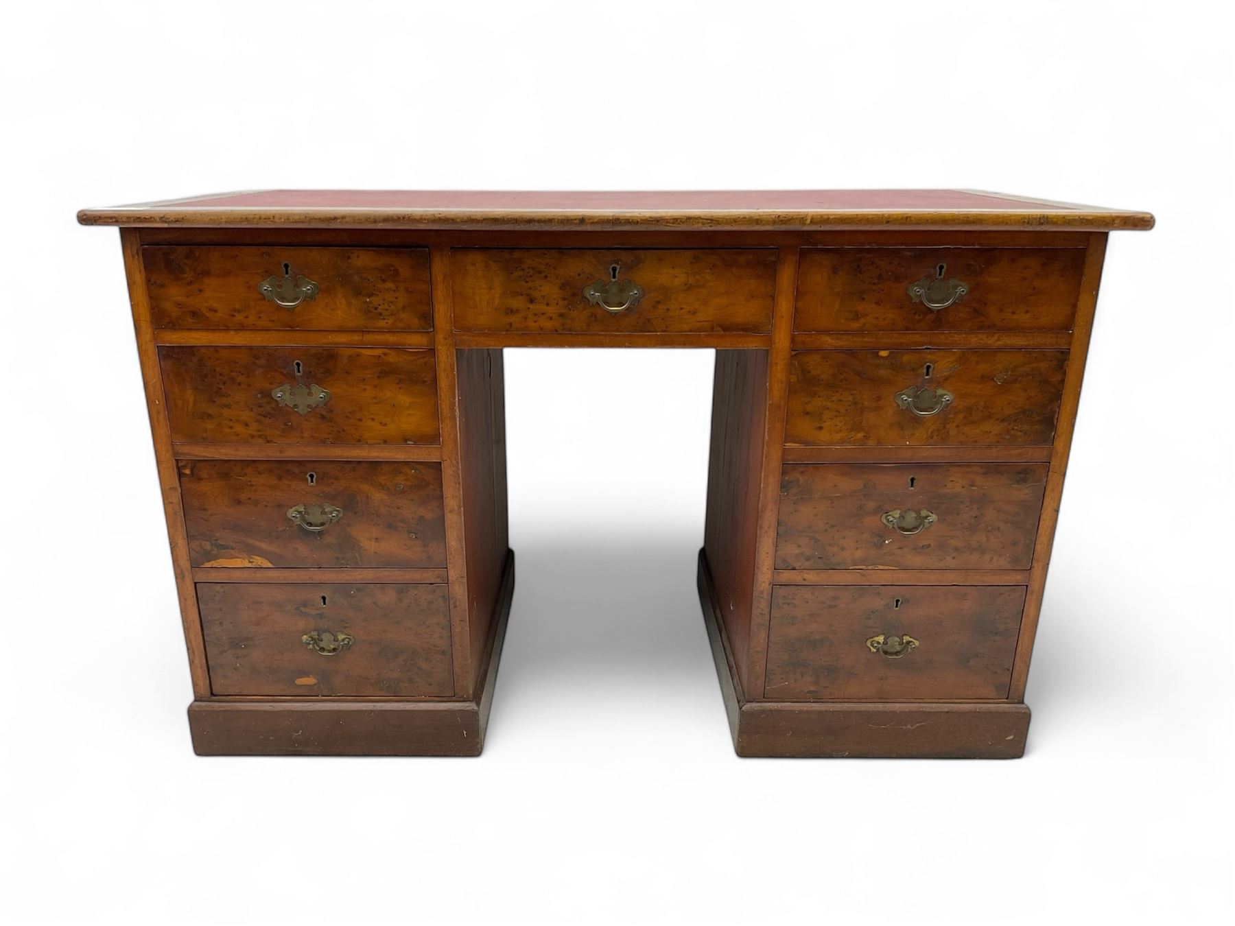 Late 19th to early 20th century walnut pedestal desk, rectangular top inset with red tooled leather writing surface, over a central frieze drawer flanked by two pedestals, each fitted with four graduated drawers with brass escutcheons and drop handles, the whole raised on a plinth base