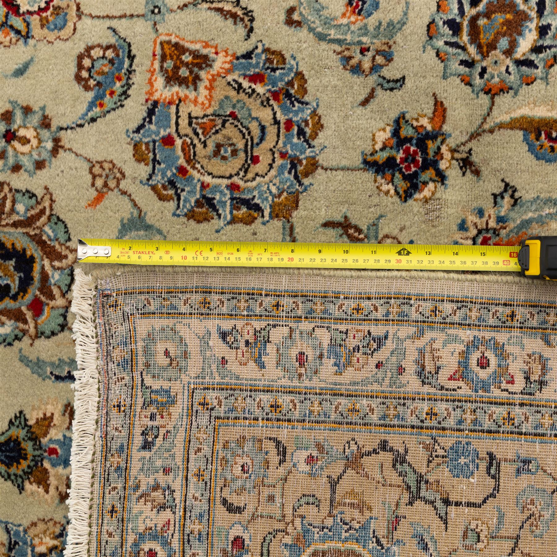 Central Persian Kashan hand-knotted carpet, cream ground with radiating floral rosette medallion in soft blue and terracotta, the field filled with stylised blooms, cloudband vines and palmette motifs, enclosed by triple borders featuring lotus and boteh designs, with cotton fringe ends 