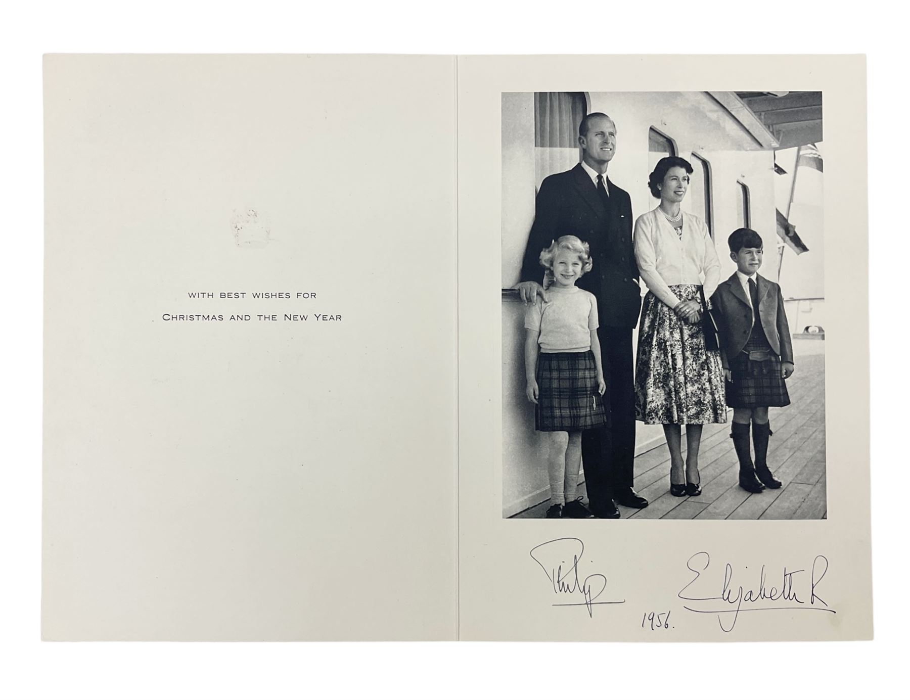 HM Queen Elizabeth II and HRH The Duke of Edinburgh - signed 1956 Christmas card with gilt embossed crown to cover, black and white photograph of the smiling Royal Couple with Prince Charles and Princess Anne on board Britannia, signed in ink 'Philip 1956 Elizabeth R',