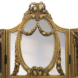 Late 19th century French Louis XIV style giltwood three fold dressing screen, each panel upholstered in floral fabric within fluted borders, with mirrored panels to tops set within moulded frames with foliate and ribbon swags 

