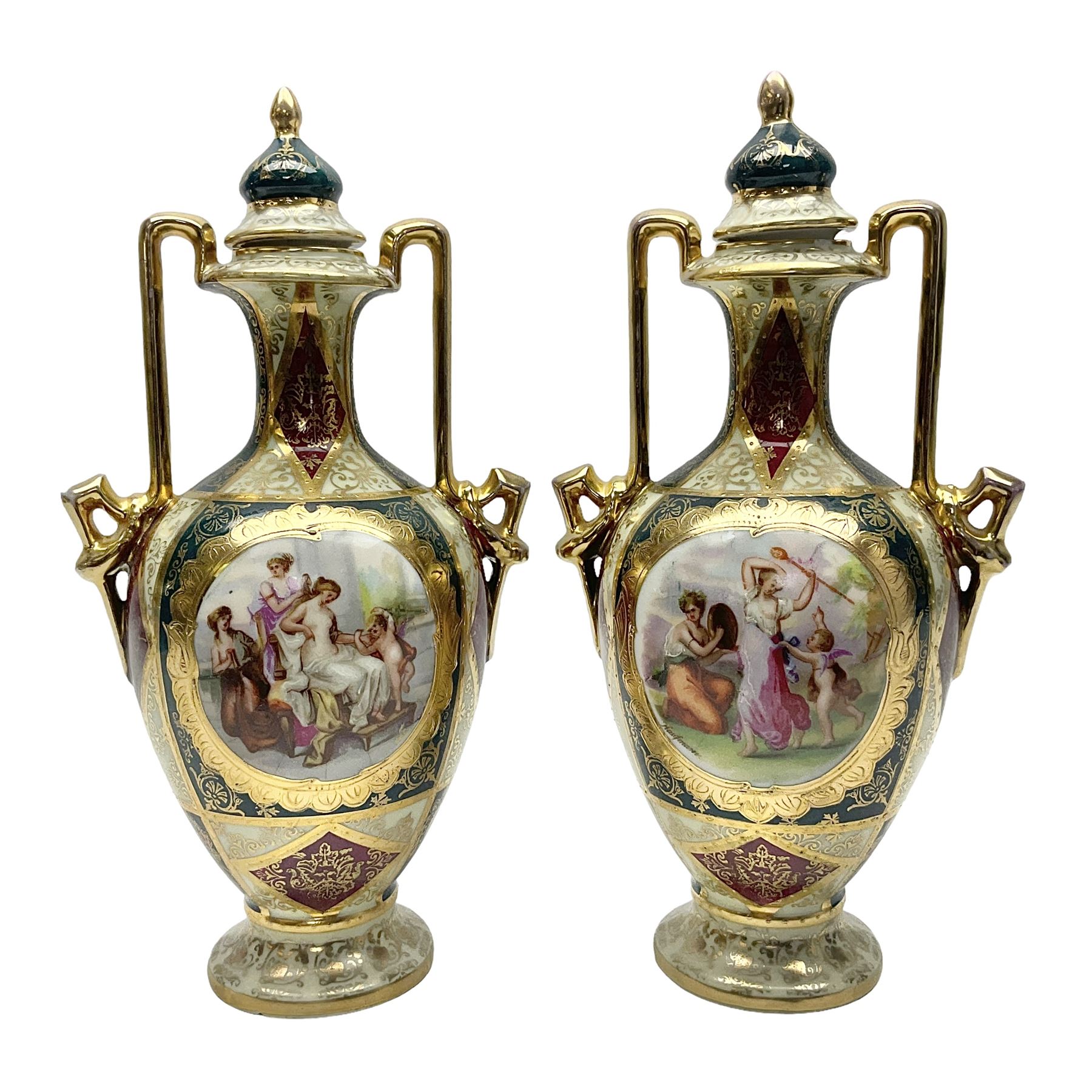 Pair of Vienna style twin handled urns and covers, decorated with figural scene on green, red and white ground with gilt highlights, stamped with beehive mark beneath, H25cm