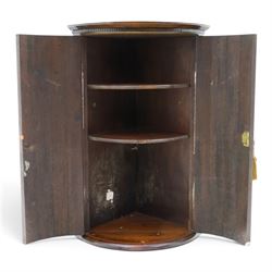 Small Georgian mahogany cylindrical hanging corner cabinet, projecting cornice with dentil carving, brass H hinges and escutcheons