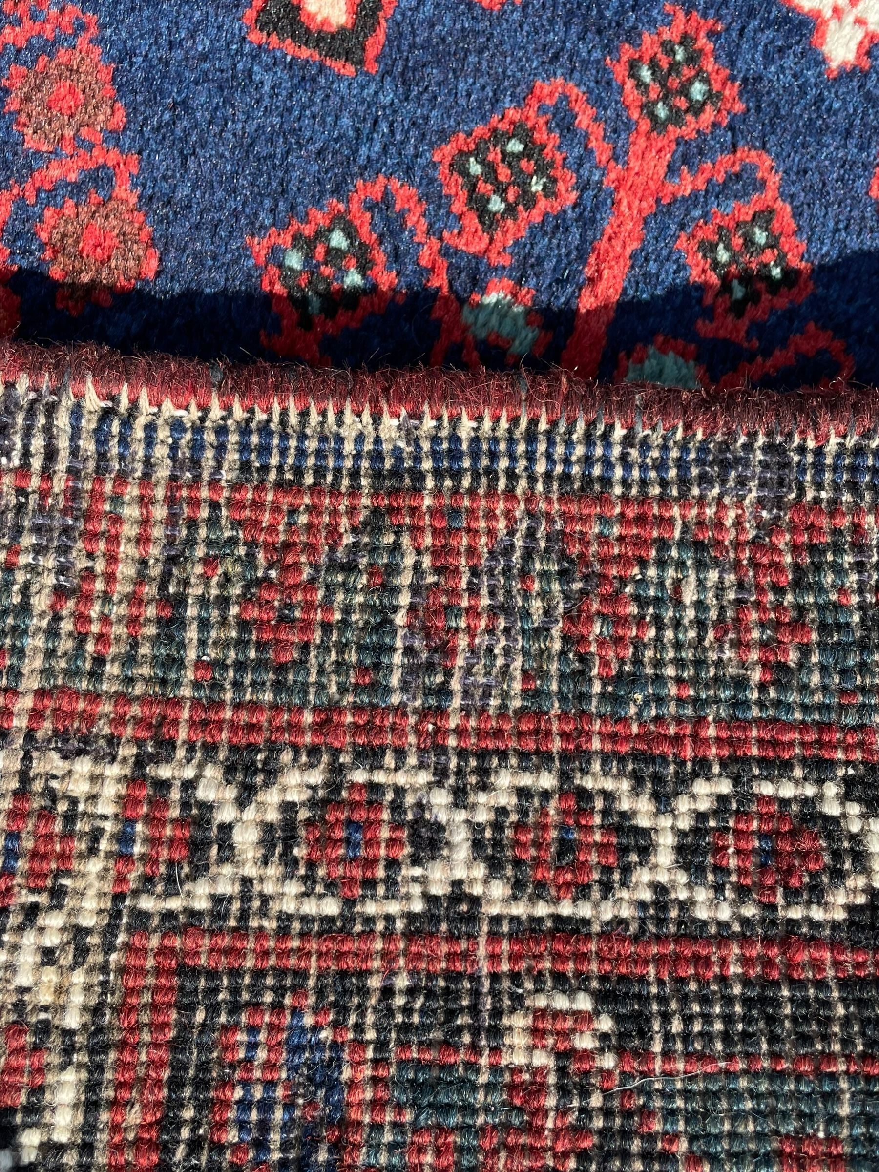 Persian Joshaghan crimson ground rug, stepped lozenge medallion surrounded by repeating foliate lozenge motifs, the border decorated with stylised plant motifs, within geometric guard stripes