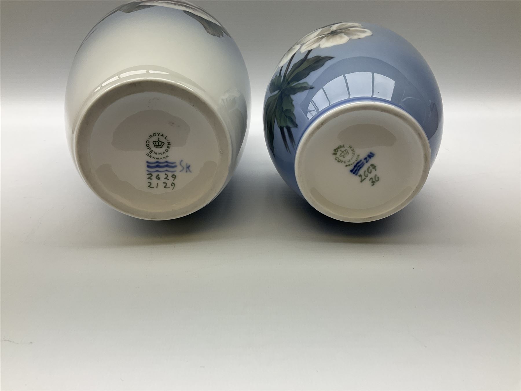 Two Royal Copenhagen vases, first example a vase of baluster form with apple blossom design on a pale blue ground, model no 2629 design no 2129 H27.5cm, second example a vase of ovoid form, with flower and butterfly decoration, model no 2667 design no 36 H17.5cm. 