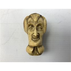 19th century carved ivory walking cane handle, modelled as the head of a greyhound with inset glass eyes, together with a further 19th century ivory example, modelled as a caricature of a gentleman's head, (2)