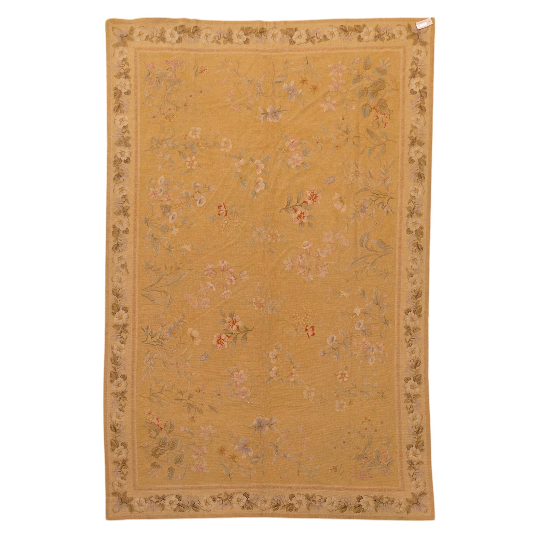 20th-century Aubusson-style woven tapestry of rectangular form with mustard yellow field decorated with scattered floral sprays in soft pastel tones of pink, cream, and muted green, within a narrow guard stripe with an outer border of trailing blossoms and foliage 