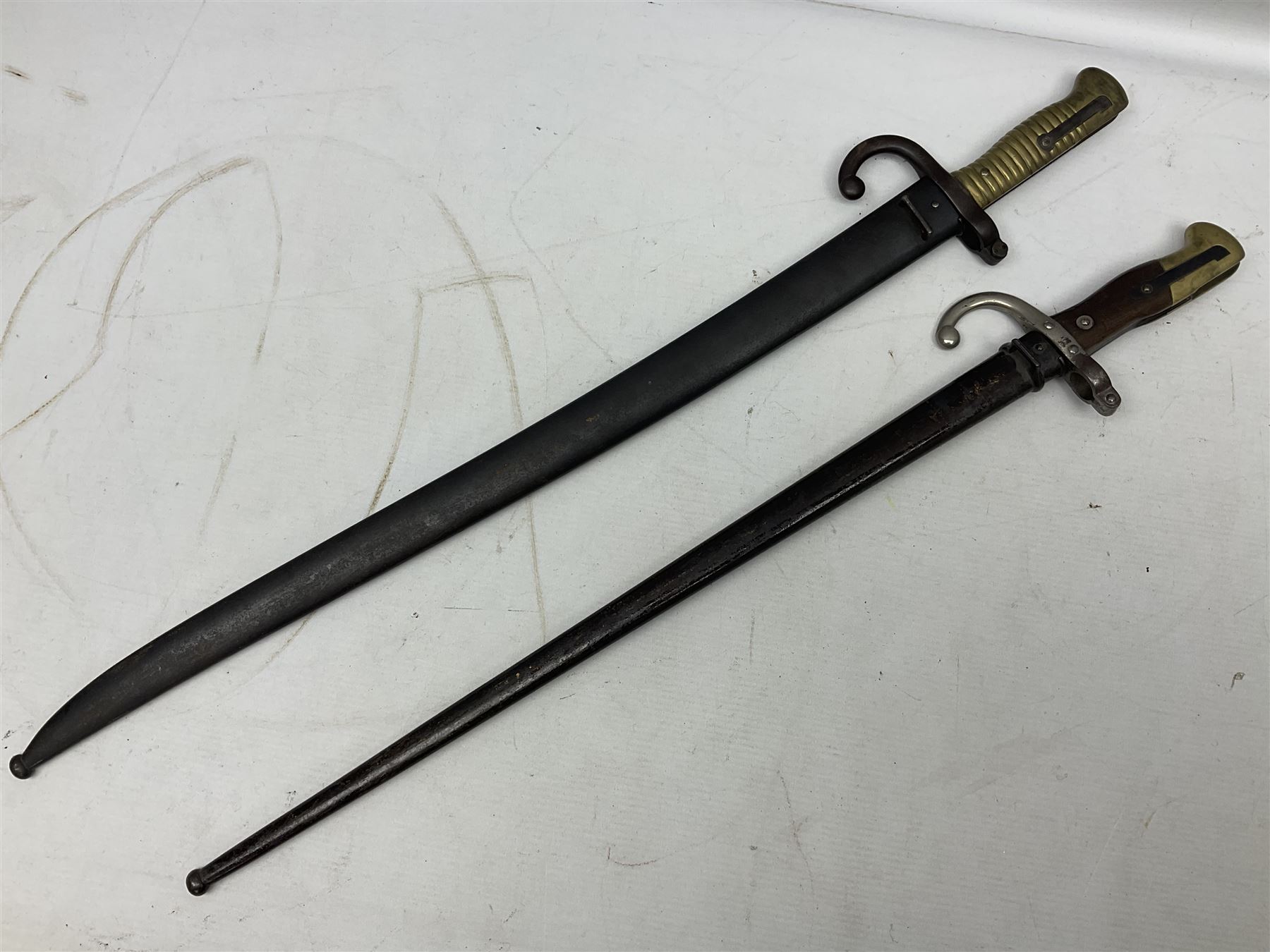 French Model 1866 Chassepot bayonet with 57cm curving fullered steel blade dated 1873 No.L63963; in steel scabbard with conforming number L71.5cm overall; and French St. Etienne Gras bayonet dated 1878 No.K10674 in steel scabbard numbered 79437 (2)