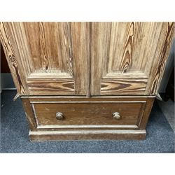Victorian pitch pine double wardrobe, projecting moulded cornice over two panelled doors, the interior fitted with hanging rail and hooks, single drawer to base