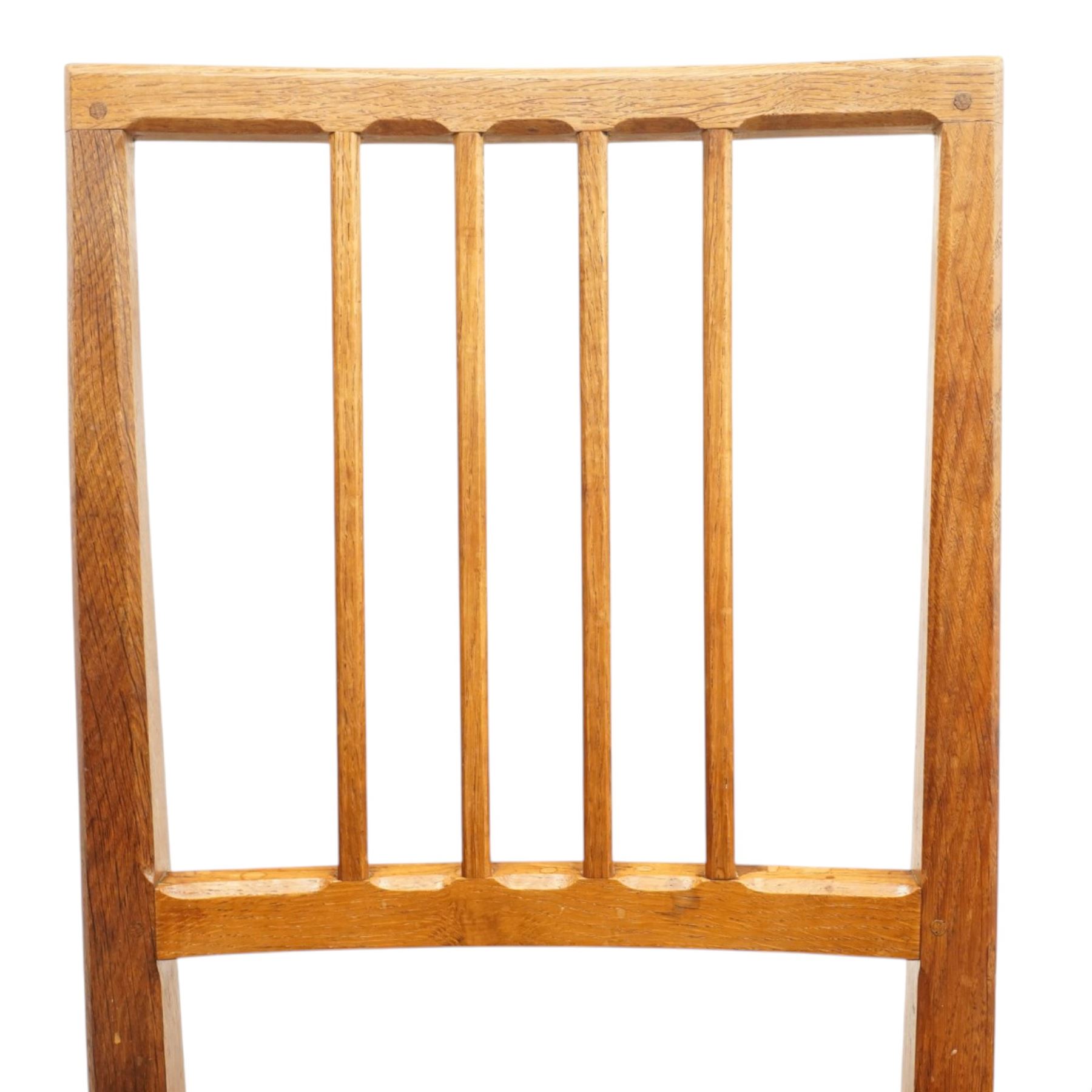 Acornman - set of four oak dining chairs, chamfered slatted back, tan leather drop in seat, raised on square supports with carved acorn signature, by the workshop of Alan Grainger of Brandsby