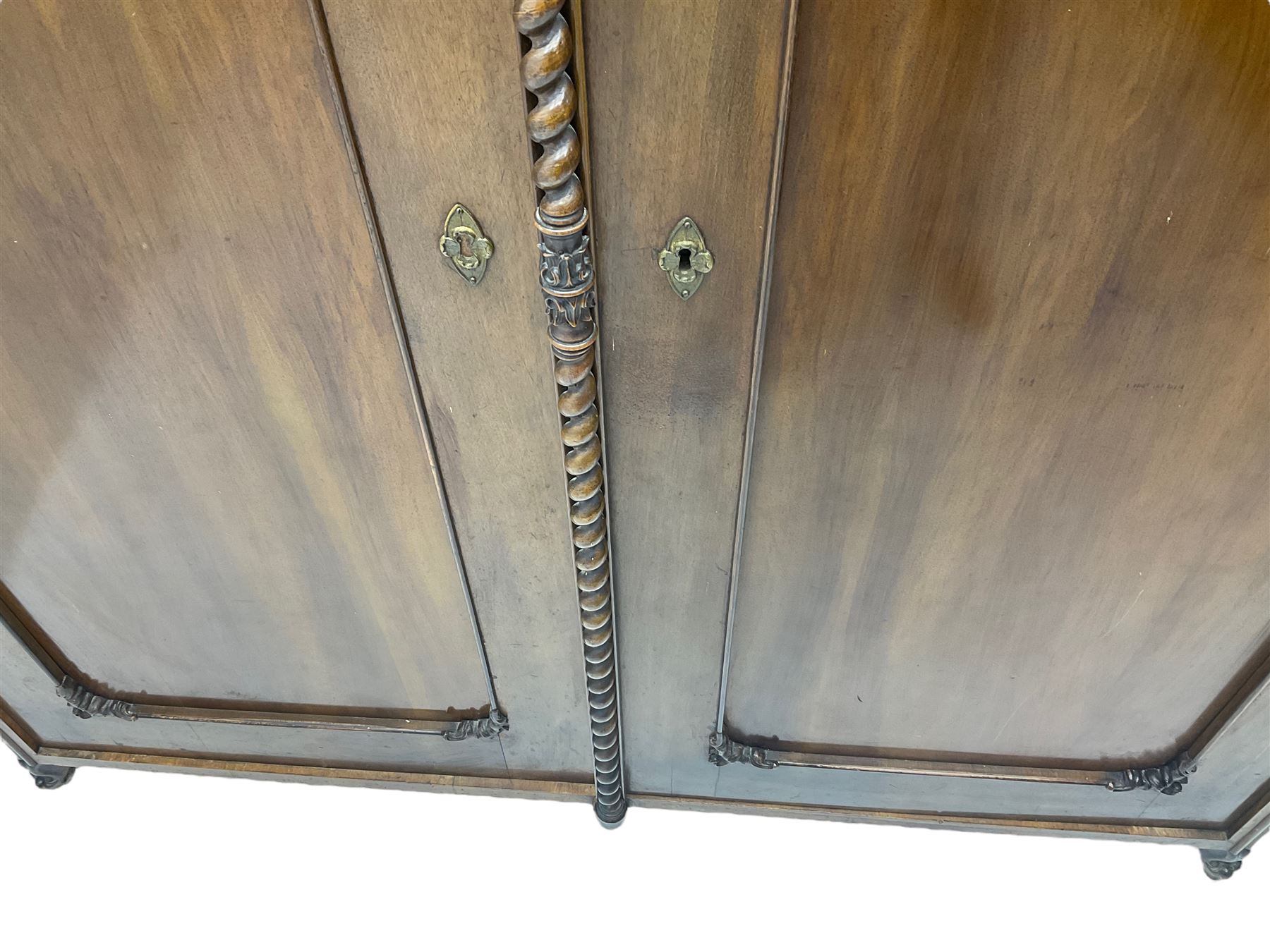 Early 20th century Italian walnut armoire wardrobe, the pierced and scrolling pediment carved with acanthus leaf detail, flanked by two scrolling cartouche with matching corbels below, the two panelled doors with applied carved rinceaux slips, with a central spiral turned upright, enclosing single shelf and hanging rail, raised on scroll feet