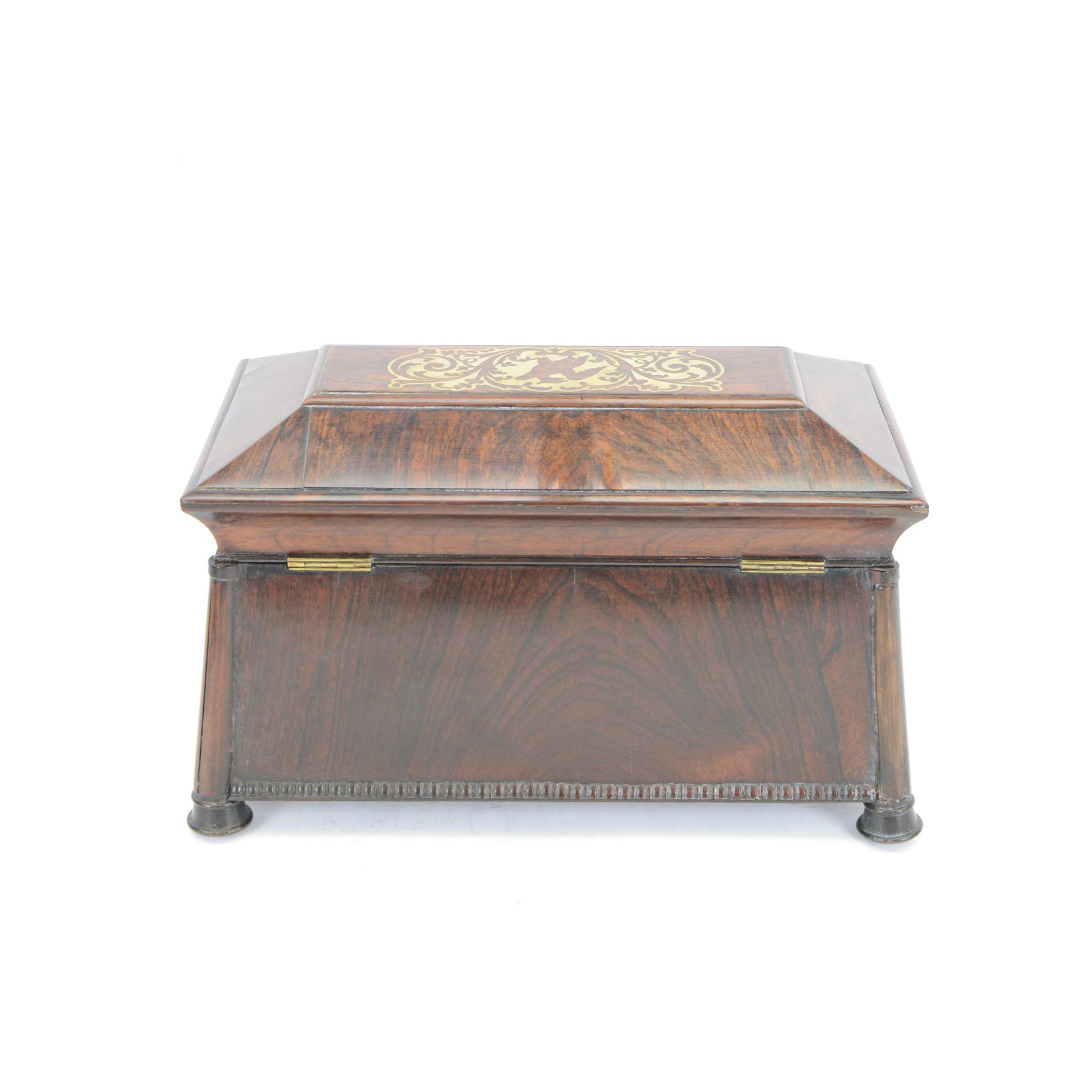 Early 19th century rosewood and brass inlaid tea caddy, of sarcophagus form, the front and hinged opening cover inlaid with brass scrolling panels, opening to reveal a compartmented interior with twin removable boxes with conforming inlaid brass detail to the hinged covers and zinc lining to the interiors, flanking a later glass mixing bowl, the whole upon four turned cylindrical feet, H21cm W36cm D20cm