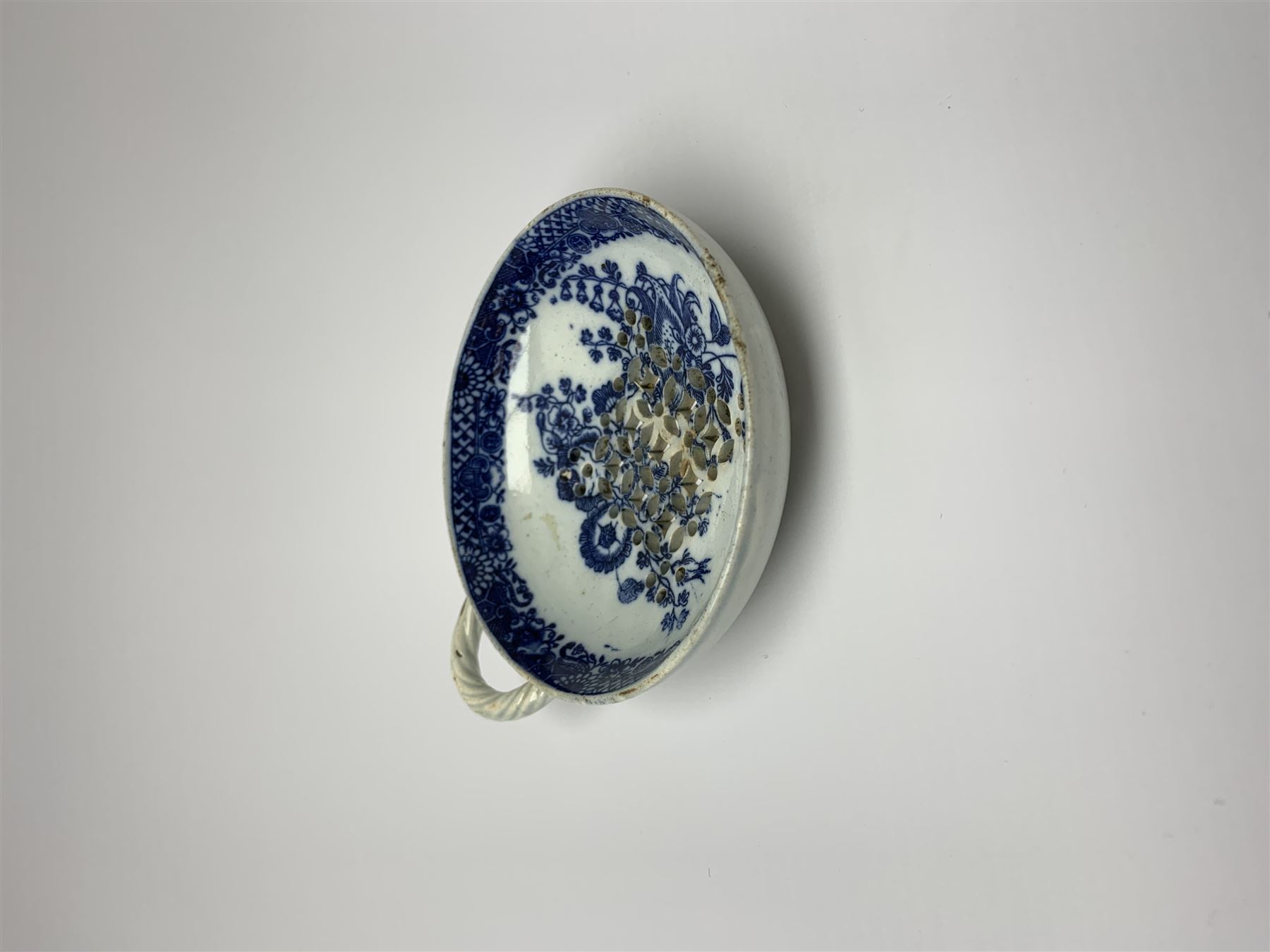 Late 18th/early 19th century Leeds Pottery egg drainer, the pierced bowl of circular form decorated with blue transfer printed floral spray and floral border, the twisted handle with foliate mounts, bowl D9cm