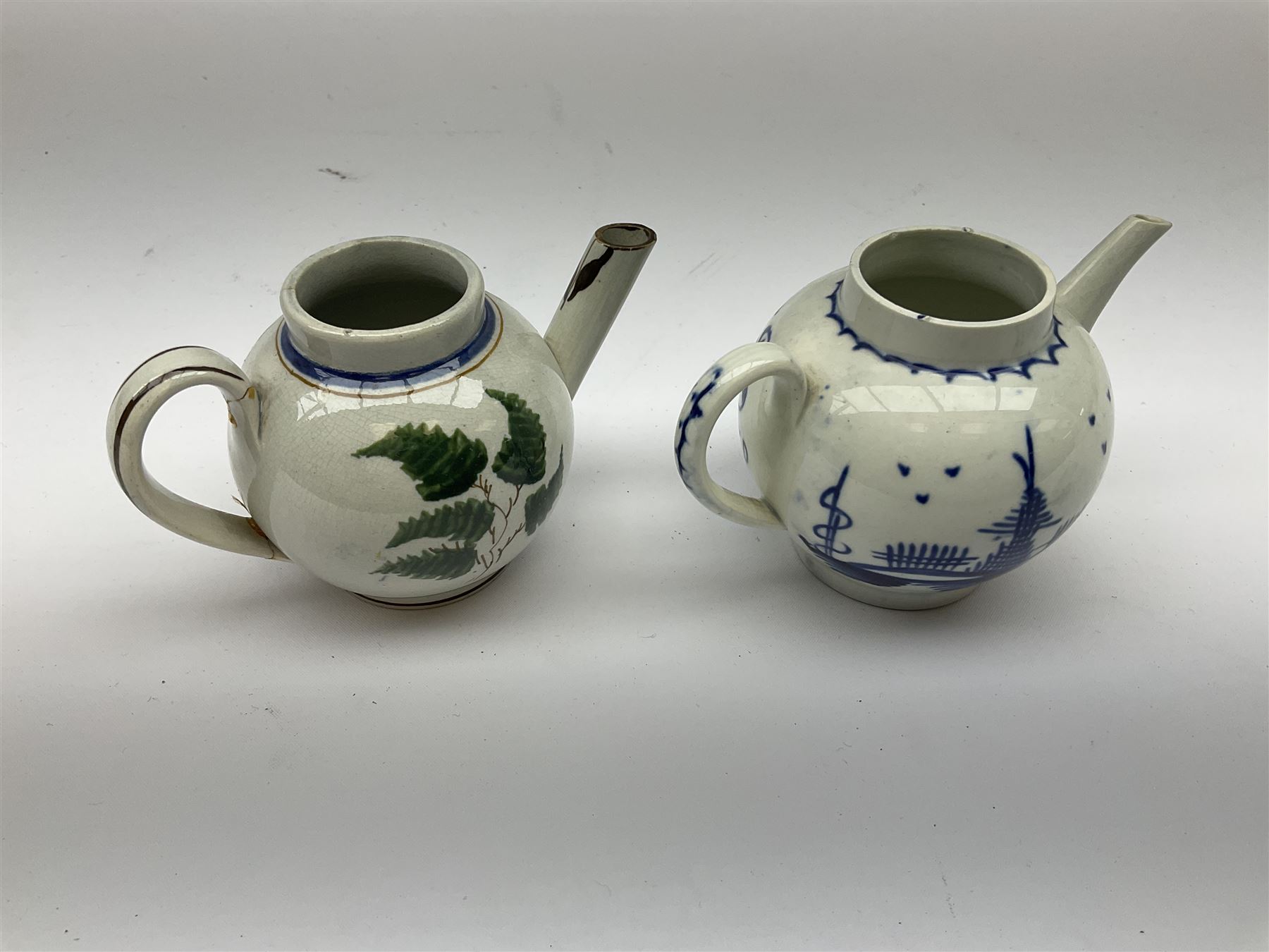 Two 18th century miniature or toy pearlware teapots, the first example lacking cover decorated with an exotic bird, the second with cover painted in underglaze blue with hut and fence, second example approximately H8cm