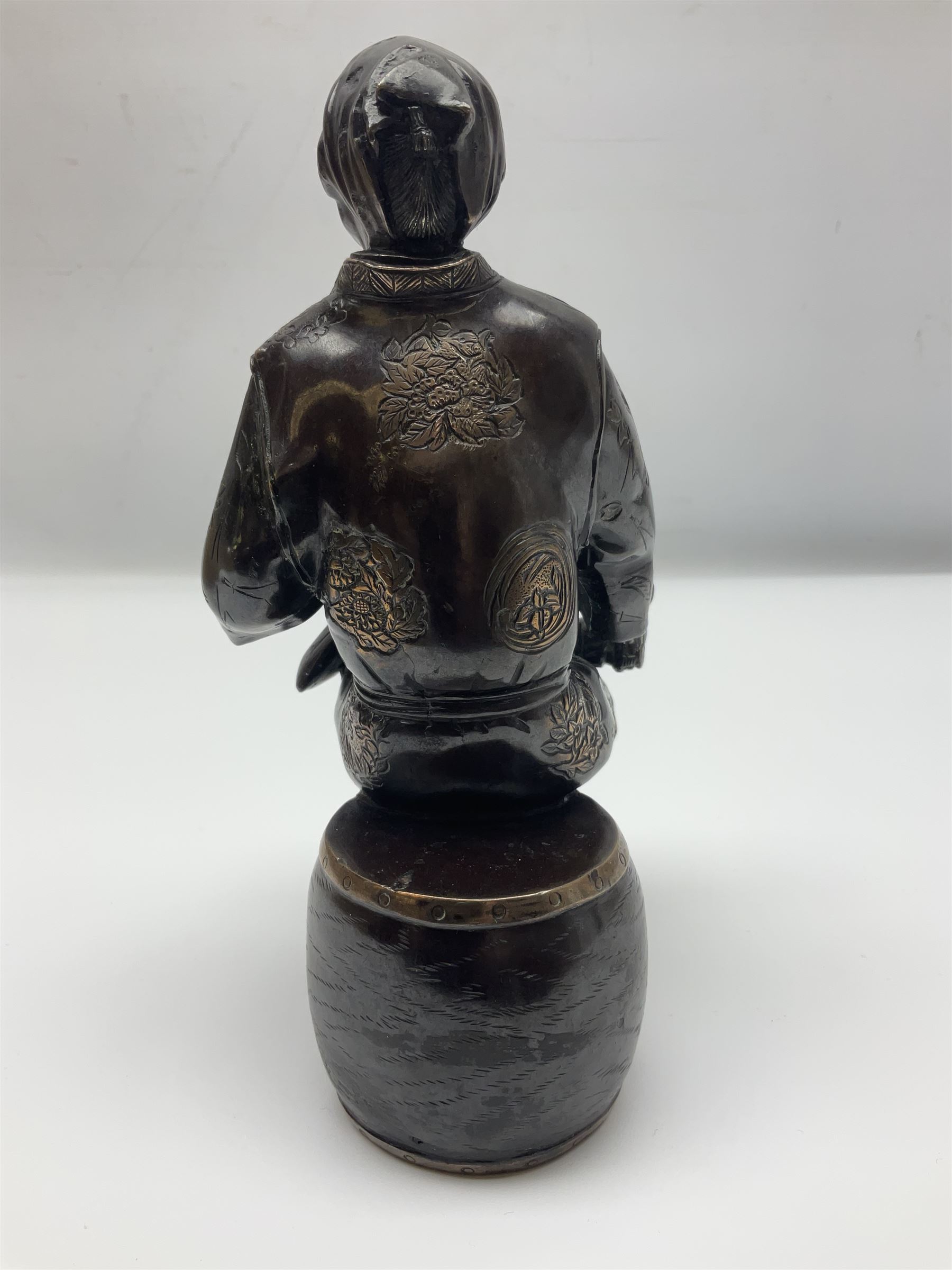 Oriental bronze figure of a gentleman, modelled seated upon barrel with a pipe in one hand and a flask in the other, H21cm