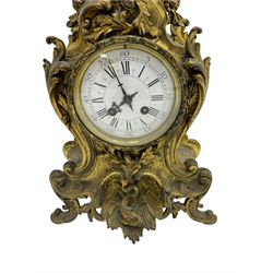 French - late 19th century 8-day gilt brass mantle clock surmounted by an urn, with a waisted case and baroque decoration raised on four splayed feet, with a glazed bezel, enamel dial with Roman numerals, five minute Arabic's and gothic steel hands, count wheel striking movement, striking the hours and half-hours on a bell. With pendulum.