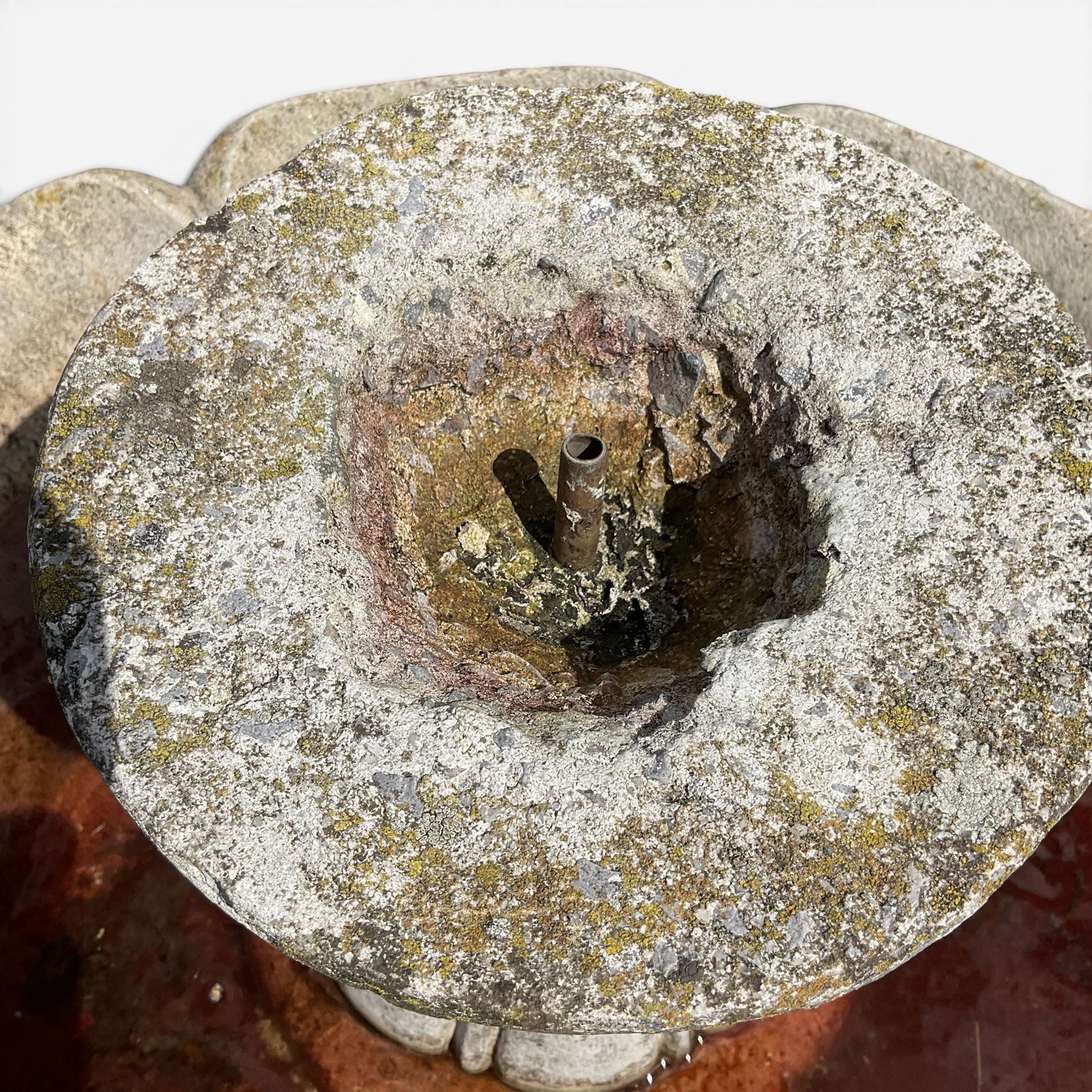 Weathered cast stone garden water feature fountain, the raised central spout with egg-and-dart moulding, within a scalloped basin raised on a lappet pedestal with cylindrical plinth base