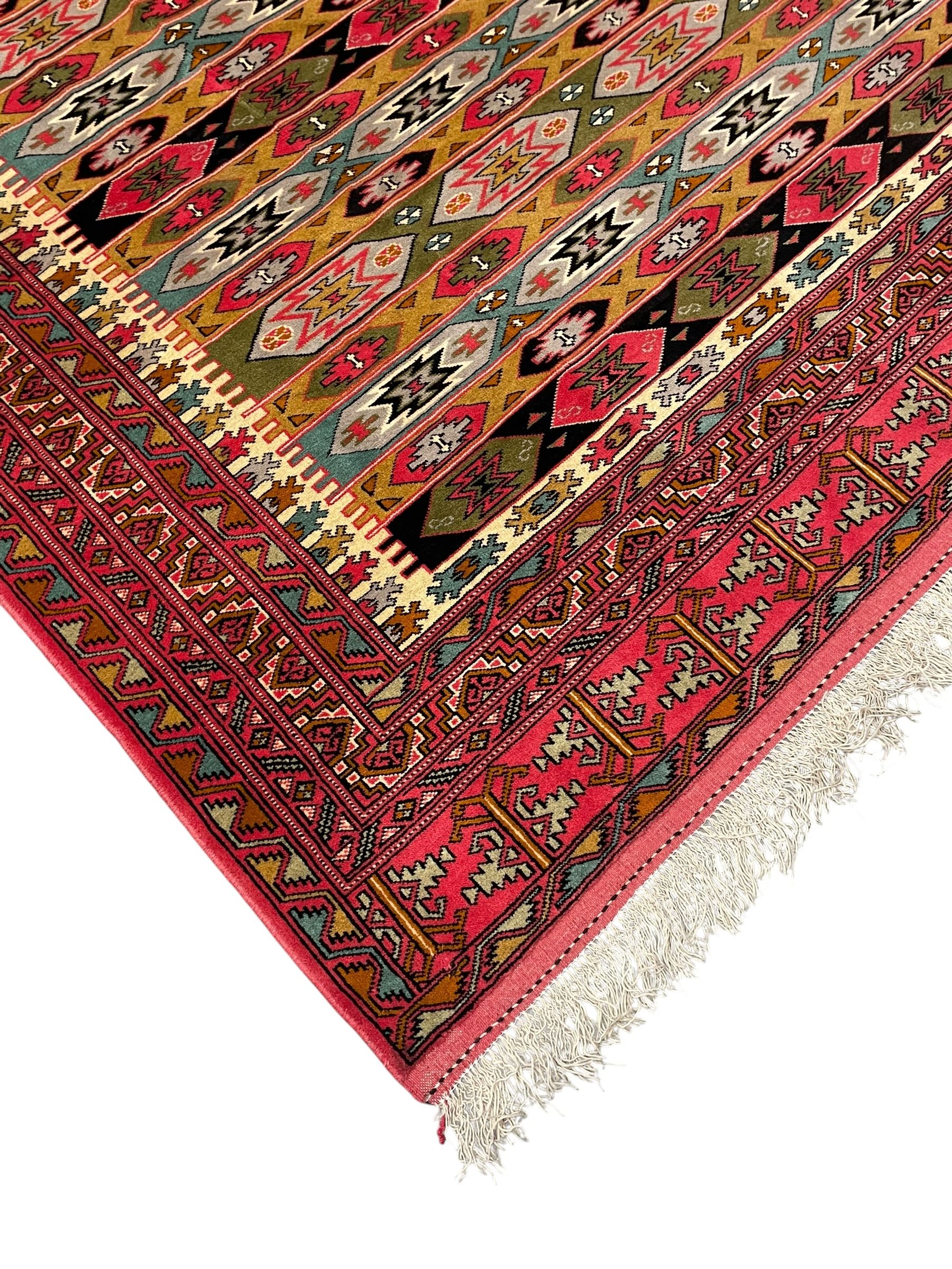 Persian red ground rug, the field divided into horizontal rows and decorated with geometric motifs, intricately pattern borders and end panels