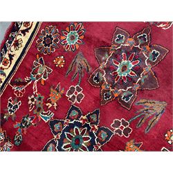 Persian rug, red ground field decorated with stylised flower heads and bird motifs, floral scrolling border