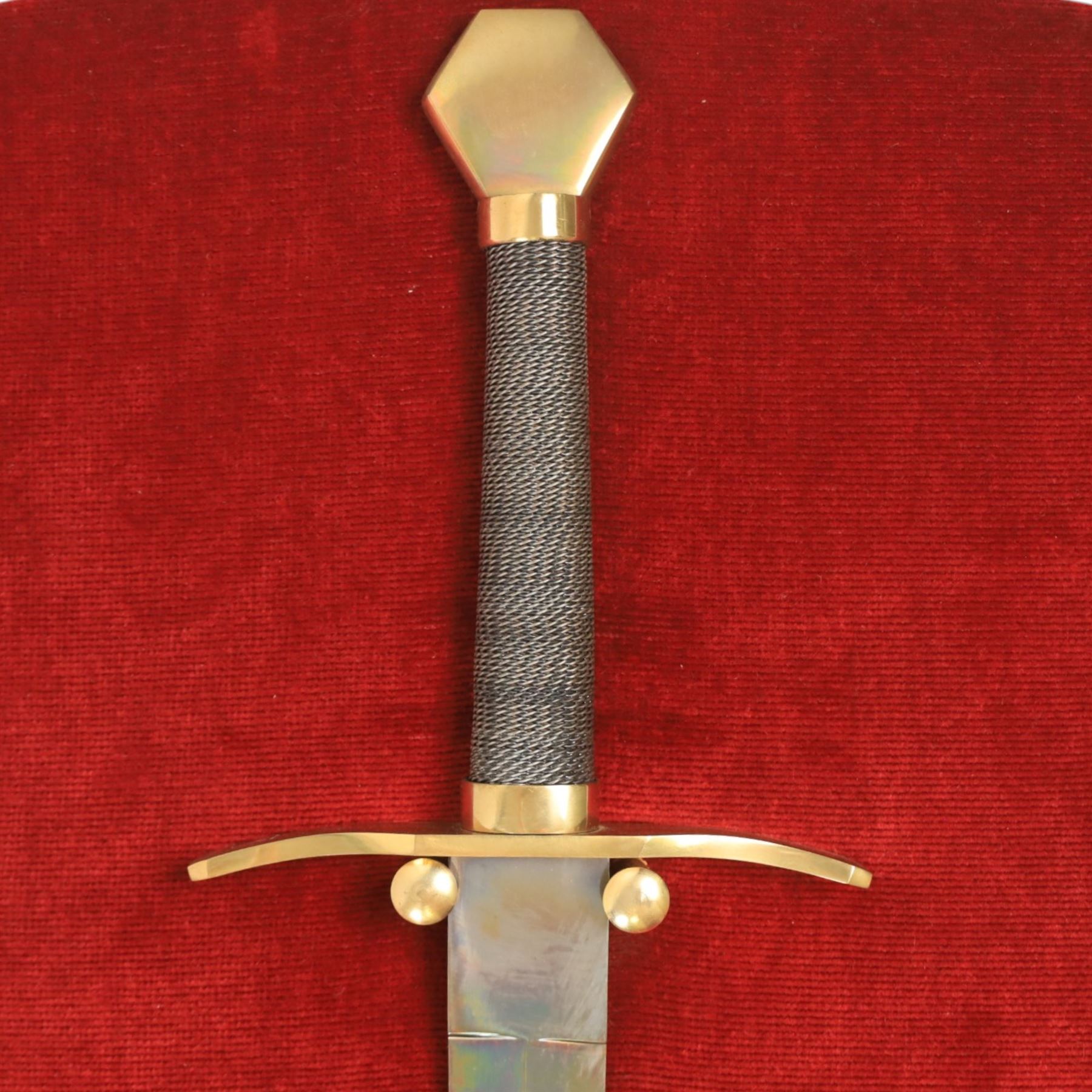 Three replica gauntlets, each housed upon a red wall shield, two with daggers, the third with a sword, largest H102cm