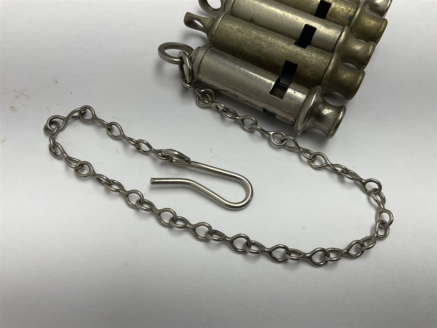 Three Hull City Police 'Metropolitan' whistles by J. Hudson 13 Barr Street Birminham, each with impressed collar number; another 'Metropolitan' police whistle with chain; and an ARP whistle by Hudson & Co with chain (5)