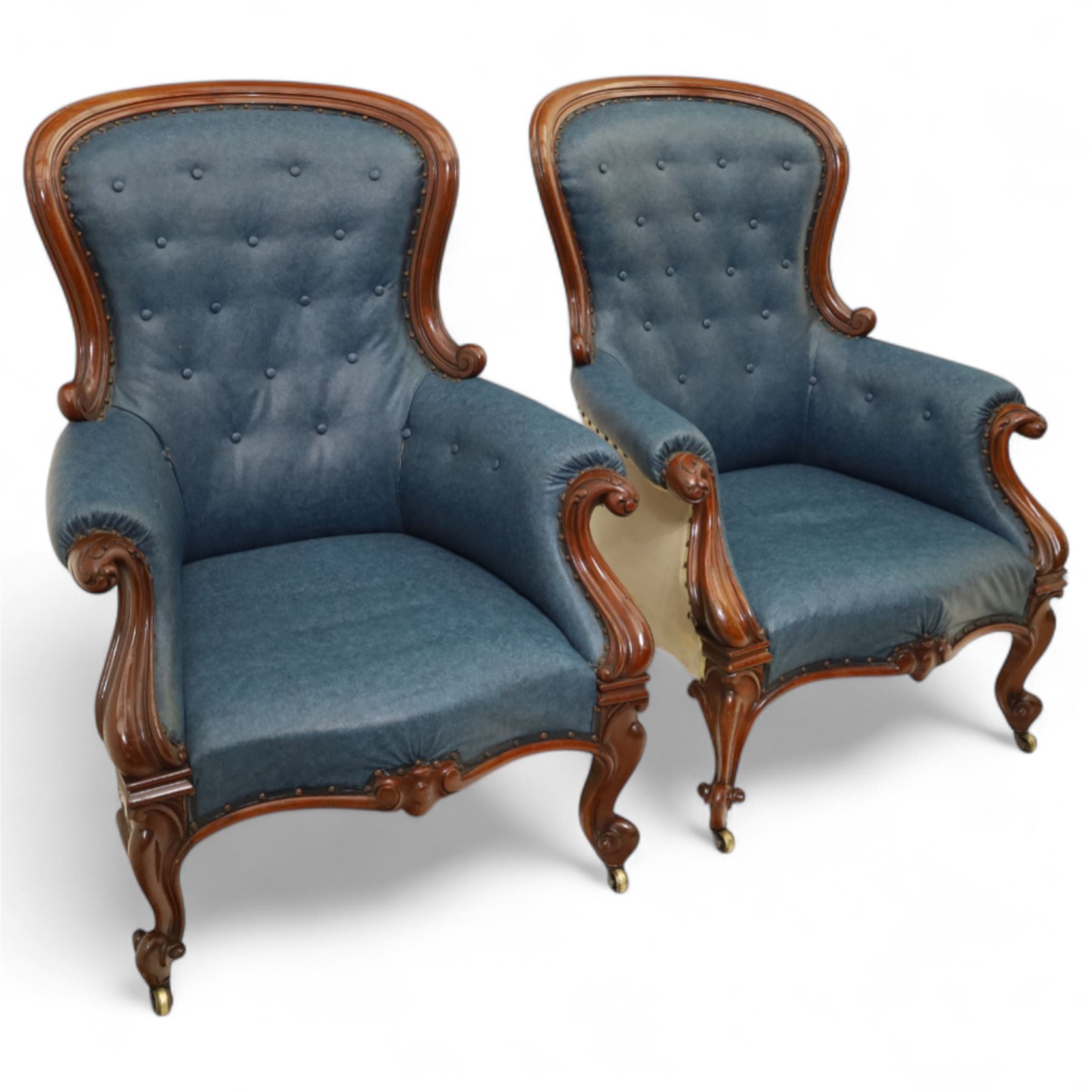 Fine pair of mid-19th-century mahogany library armchairs, carved frame with balloon-shaped back with scrolled ends, rolled wide arms, ending in a scrolled volute above a serpentine seat rail, upholstered in mottled turquoise faux leather, button upholstered back, arms, and cushion seat, studded sides and apron, raised on scroll carved front feet and splayed rear legs on castors 