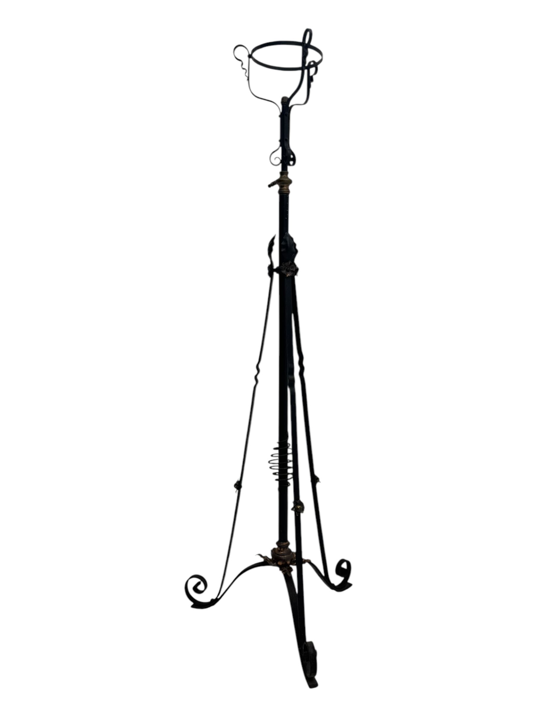 Late 19th century wrought iron and brass pulpit lamp, featuring an adjustable stem with a spiral twist detail, brass foliate mounts, and a tripod base with scrolled feet and decorative floral accents