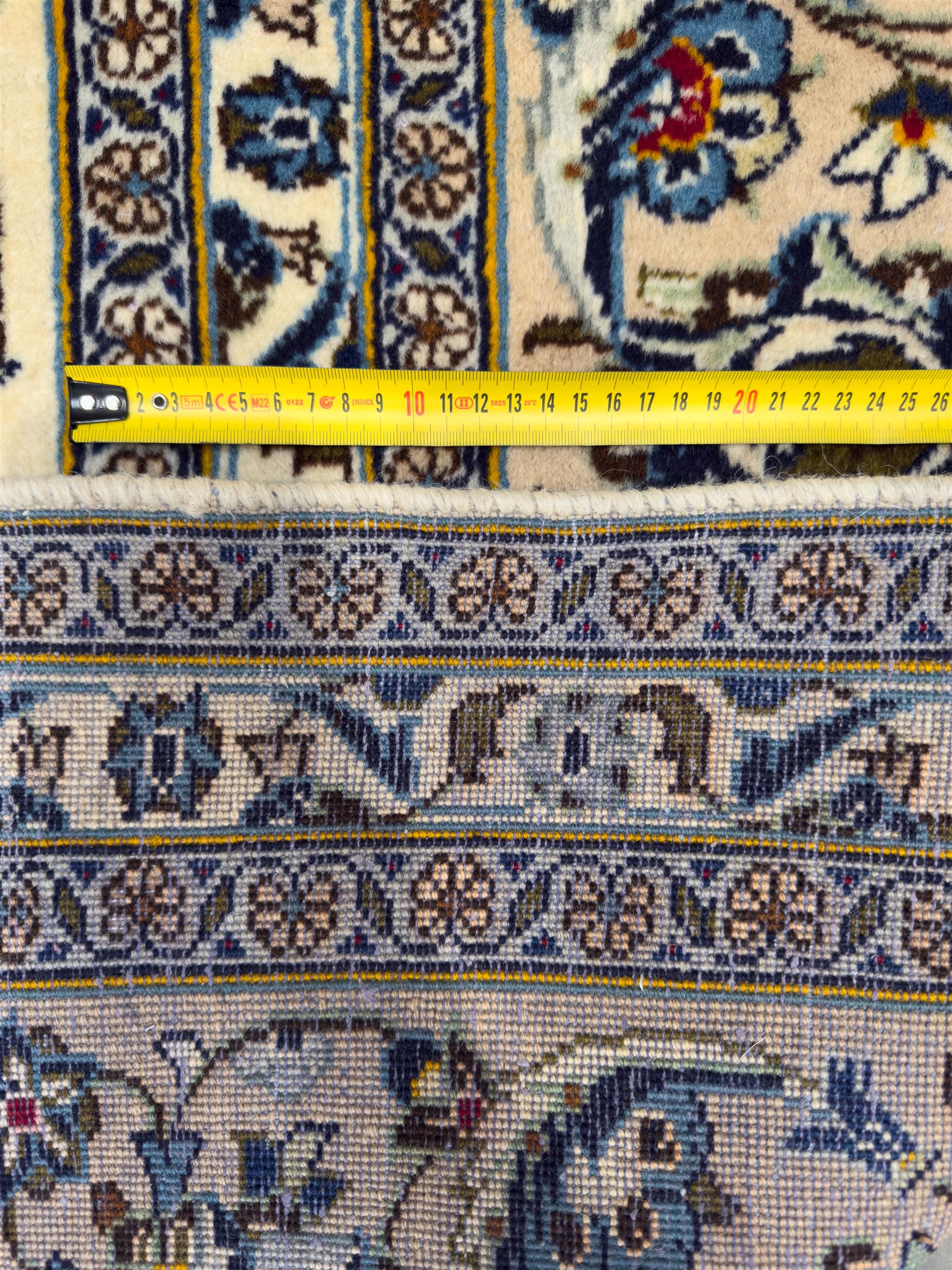 Central Persian Kashan hand-knotted carpet, ivory field with an all-over design of scrolling vines, lotus palmettes, and rosettes in shades of blue and brown within a blue ground border of palmettes and arabesques between multiple guard stripes, 
348 cm x 246cm