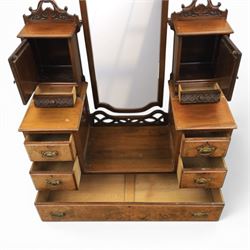 Edwardian figured walnut dressing chest, with central tilting mirror with pierced fret work, flanked by cabinet with figured walnut panelled door above a trinket drawer, with four short over a long long drawer, raised on a plinth base with castors 