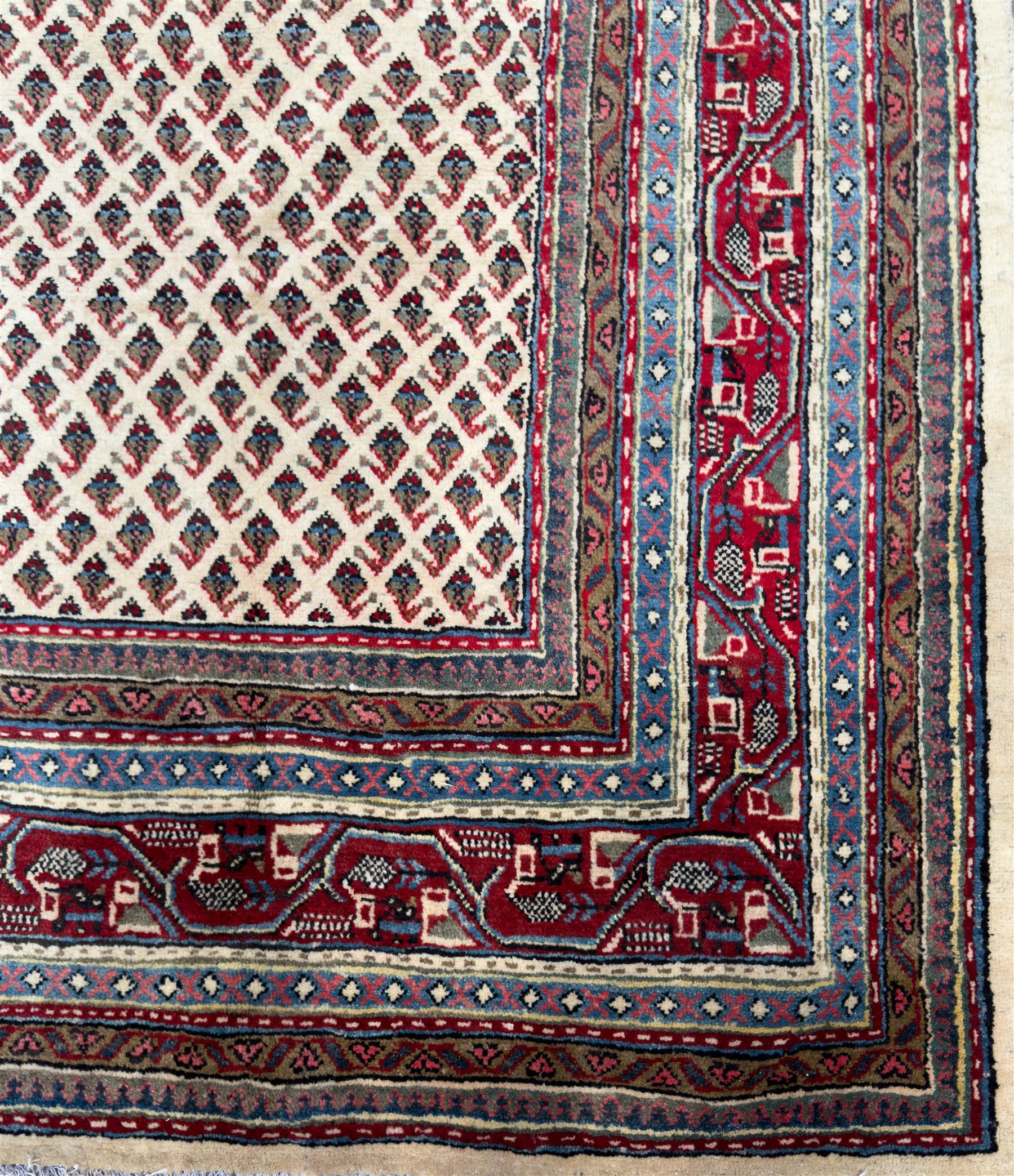 Northwestern Persian Bottehmir hand-knotted rug, ivory field with an all-over design of boteh motifs arranged in diagonal rows within multiple borders and a primary madder red field with stylized vine and flowerhead motifs, 320cm x 214cm 