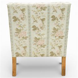 Pair of Edwardian upholstered armchairs, each with shaped padded back flanked by scroll arms, loose seat cushions, upholstered throughout in rose patterned fabric with vertical floral bands, raised on square tapering wooden legs
