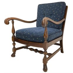Early 20th century stained beech framed armchair, cane panel back over scrolled arm terminals, raised on turned supports united by turned H-stretcher, with patterned blue upholstered loose back and seat cushions