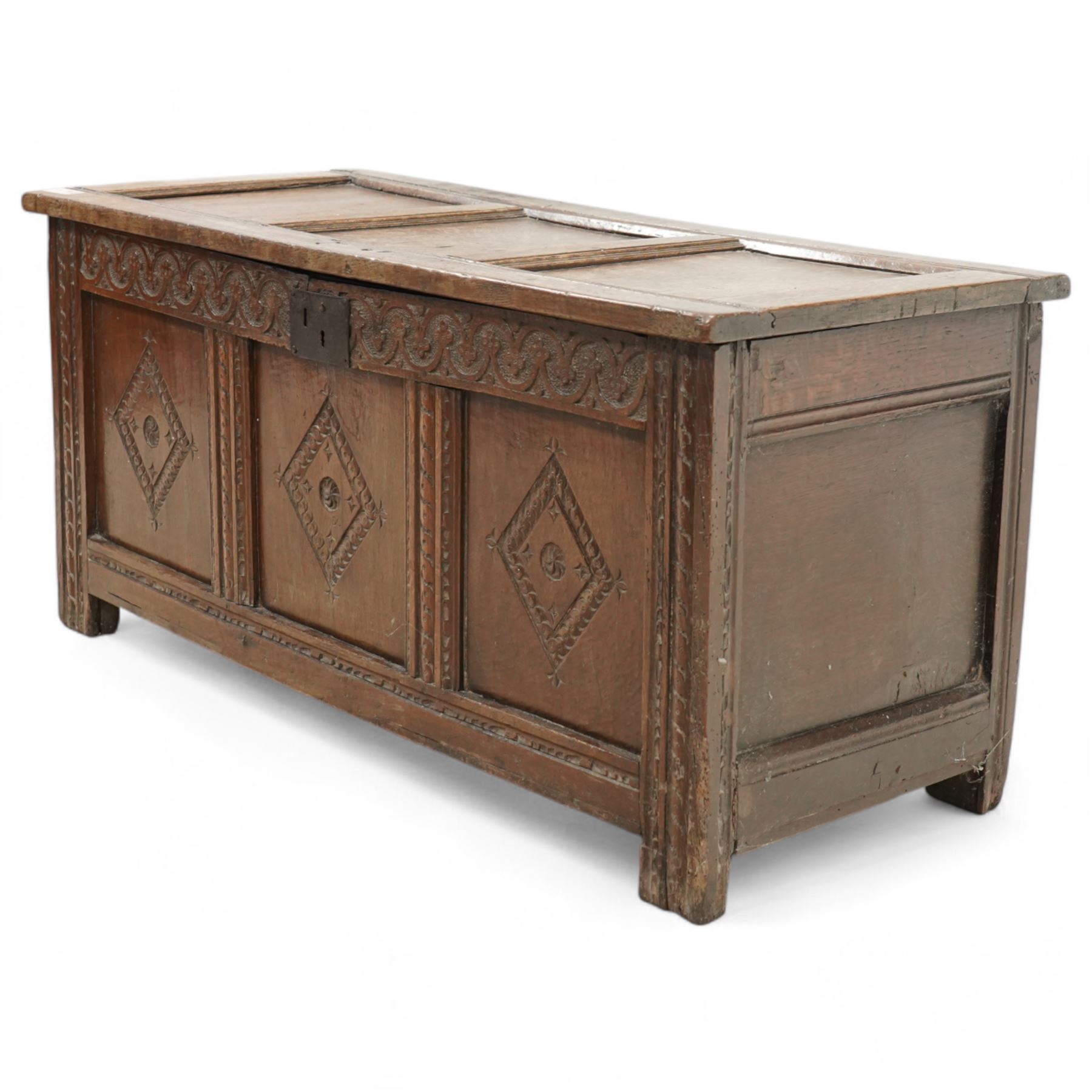 18th century oak coffer or blanket box, triple panel hinged lid over panelled front and sides, the front carved with scrolling foliate motifs and lozenges, moulded frame with chip carved decoration on stile supports 