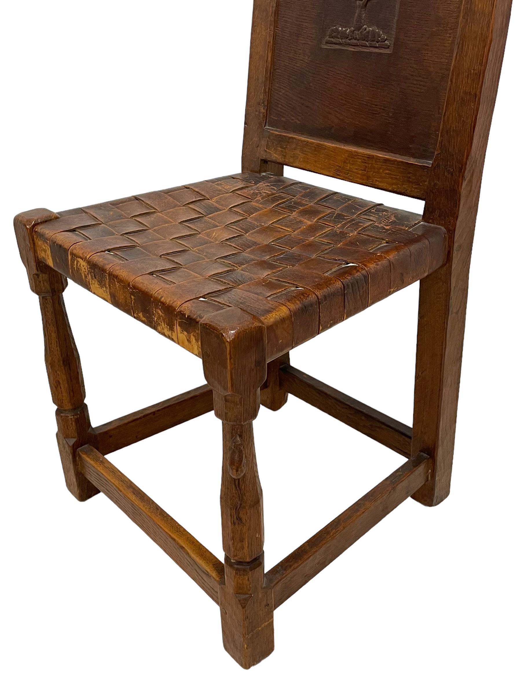 Mouseman - circa. 1930s set of six (4+2) oak dining chairs, panelled back carved with the Bagshawe family crest, the moto 'Forma Flos Fama Flatus' over an arm grasping a bugle-horn with ribbon tie and Yorkshire rose motif, adzed frame, leather lattice strap seat, on octagonal supports united by stretchers, two carvers and four side chairs, each carved with mouse signature, by Robert Thompson of Kilburn 

Provenance: Owned since manufacture by the Bagshawe family, descendants of the Staithes Group Artist Joseph Richard Bagshawe RBA (1870-1909).