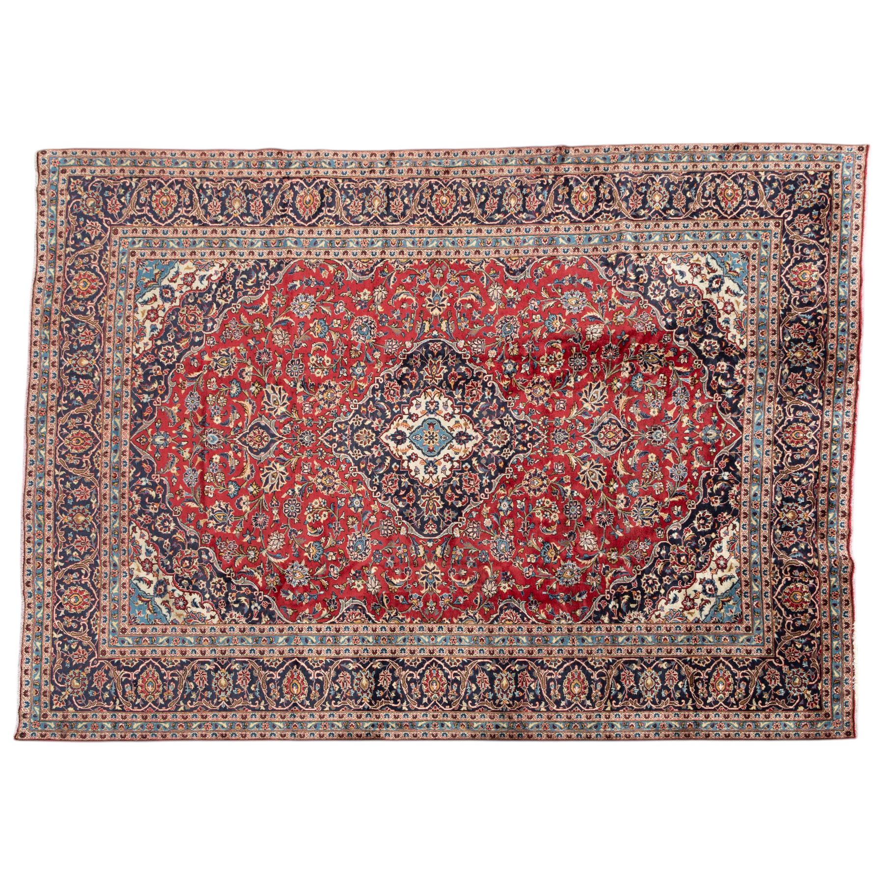 Persian Ardakan carpet, brick red field with ivory and navy central medallion, surrounded by stylised lotus blossoms and cloudband motifs, framed by rich indigo borders featuring palmettes, serrated leaves and angular vine work, woven in the city of Ardakan in central Iran