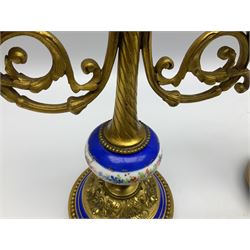 Pair of 19th century French ormolu and porcelain candlesticks, each with circular stepped foliate cast base with beaded rim and porcelain band, upon three knop feet, leading to a compressed spherical porcelain knop painted with a band of flowers between gros bleu type borders, and tapering stem with flambeau finial, supporting twin scrolling branches leading to sockets above foliate cast drips pans, H24.5cm