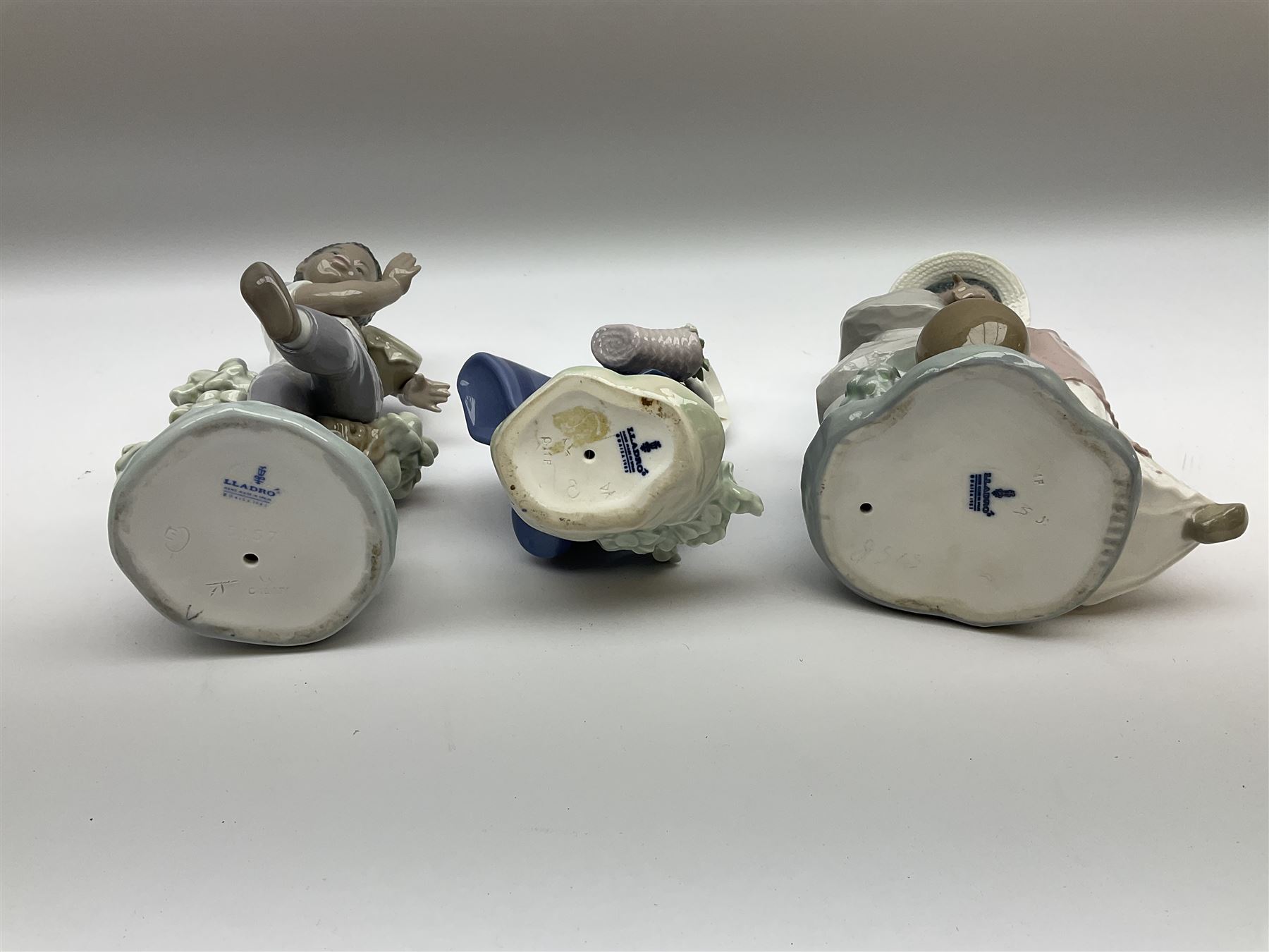 Pair of Lladro figures designed by Jose Roig, Bongo Beat no. 5157 and A Step in Time no. 5158 and a Lladro figure of a girl with a basket of flowers.
