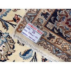 North East Persian Meshed hand-knotted rug, ivory field with scrolling vines, palmettes, and rosettes in shades of blue and brown, within a dark blue border of palmettes and flowerheads between multiple guard stripes, with cotton fringe ends  