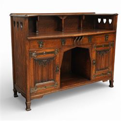 Shapland and Petter - Arts and crafts oak sideboard, rectangular overhanging top with raised open back fitted with shaped supports and pierced heart cut-outs to the ends, the base fitted with a central arrangement of two short drawers with cast metal drop handles over an open kneehole recess, flanked by a pair of cupboard doors each with linenfold panels and applied strap hinges, enclosing shelved interiors, raised on shaped bracket feet