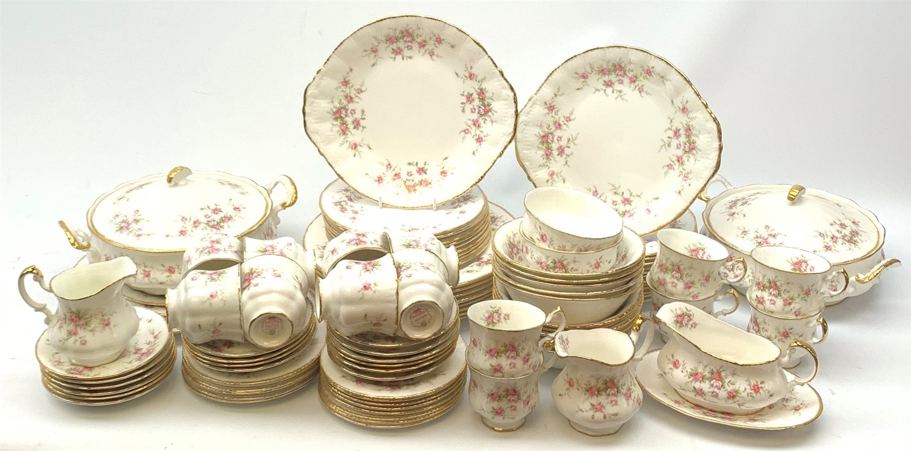 Paragon Victoriana Rose pattern tea and dinnerware, comprising fourteen teacups, sixteen saucers, fourteen side plates, two milk jugs, two open sucriers, two sandwich plates, a cake stand (lacking central support), two tureen and covers, eight dinner plates, twenty one dessert plates, eleven bowls, and sauce boat and stand. 