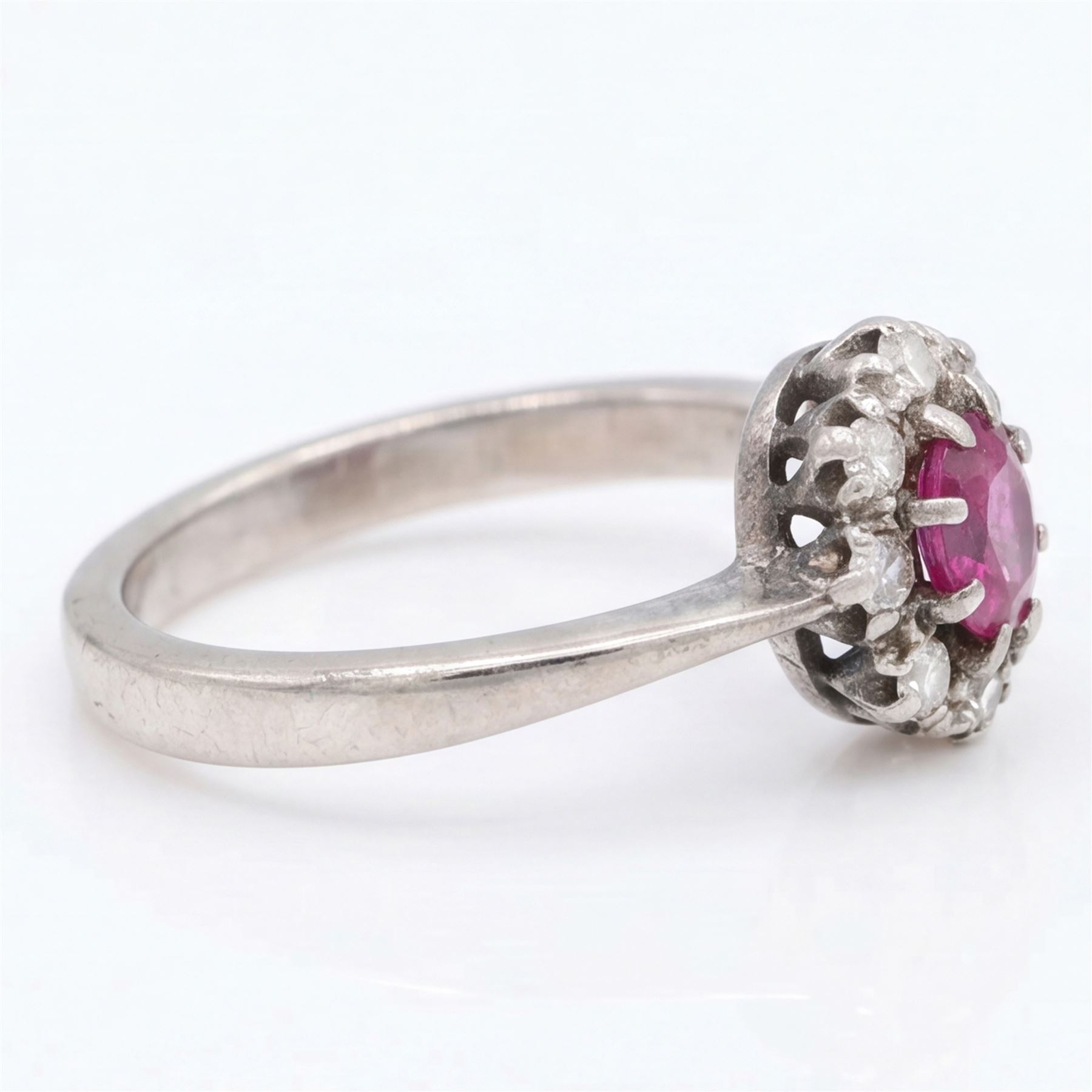 White gold ruby and diamond cluster ring, single oval cut ruby of approx 0.45 carat, surrounded by eight single cut diamonds, stamped 18ct, total diamond weight approx 0.15 carat