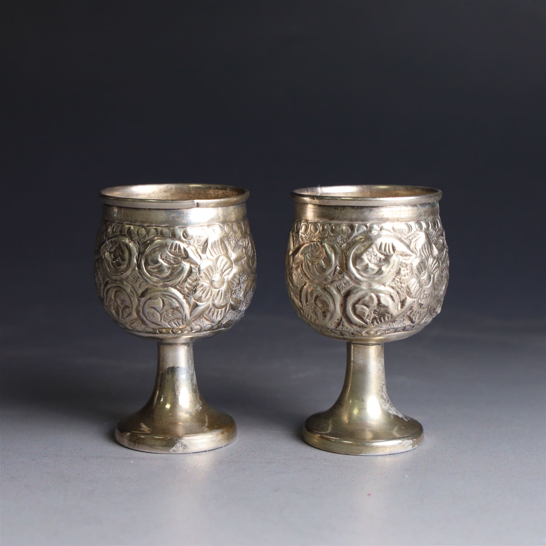 Pair of miniature Indian silver goblets, with embossed floral and foliate decoration, H6.5cm