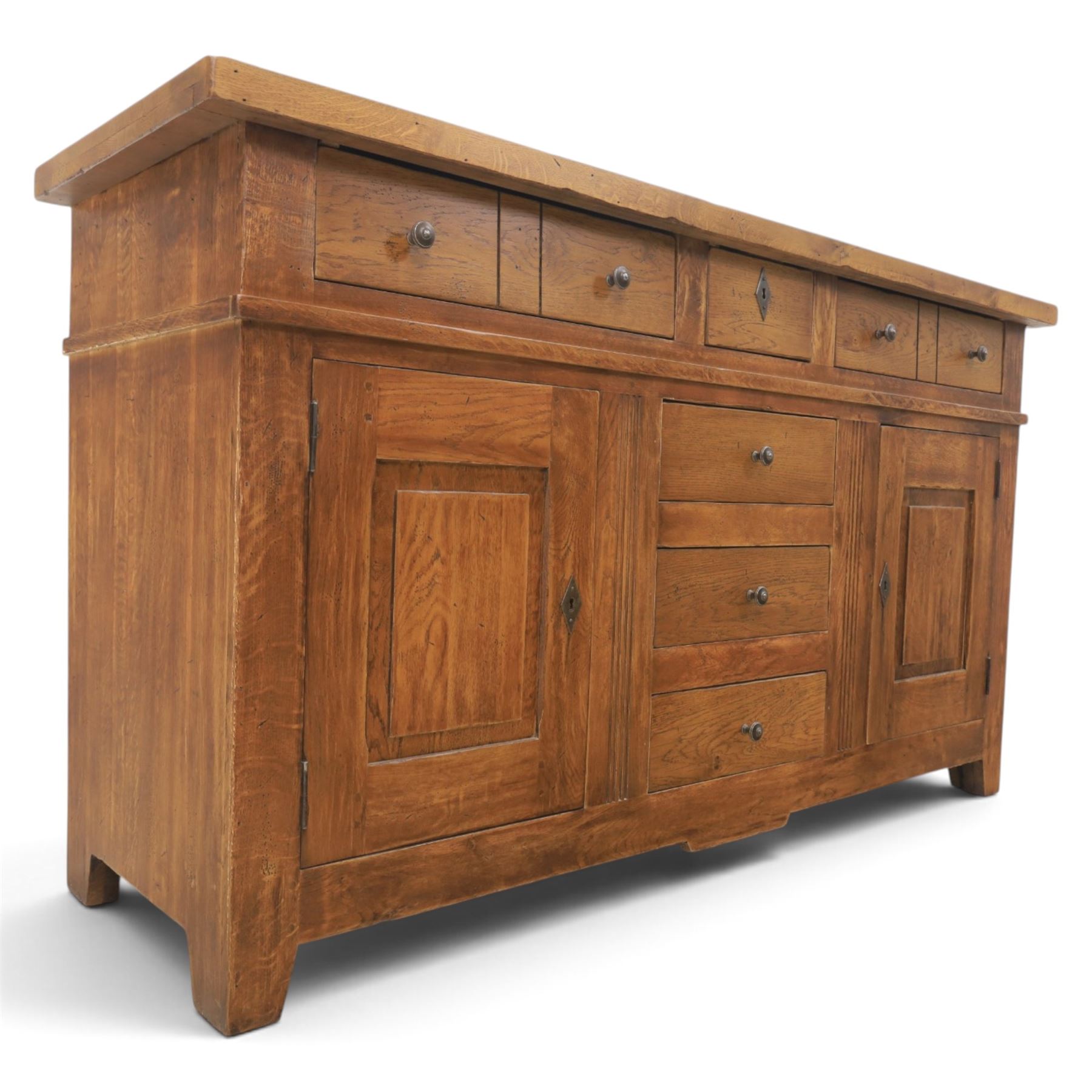 Indigo Furniture - large rustic oak sideboard fitted, with three drawers above three central drawers, flanked by fielded panelled doors, raised on bracket feet