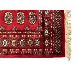 Persian Bokhara crimson ground rug, the field decorated with repeating Gul motifs and lozenges, the multi-band border with stylised plant motifs with black outlines