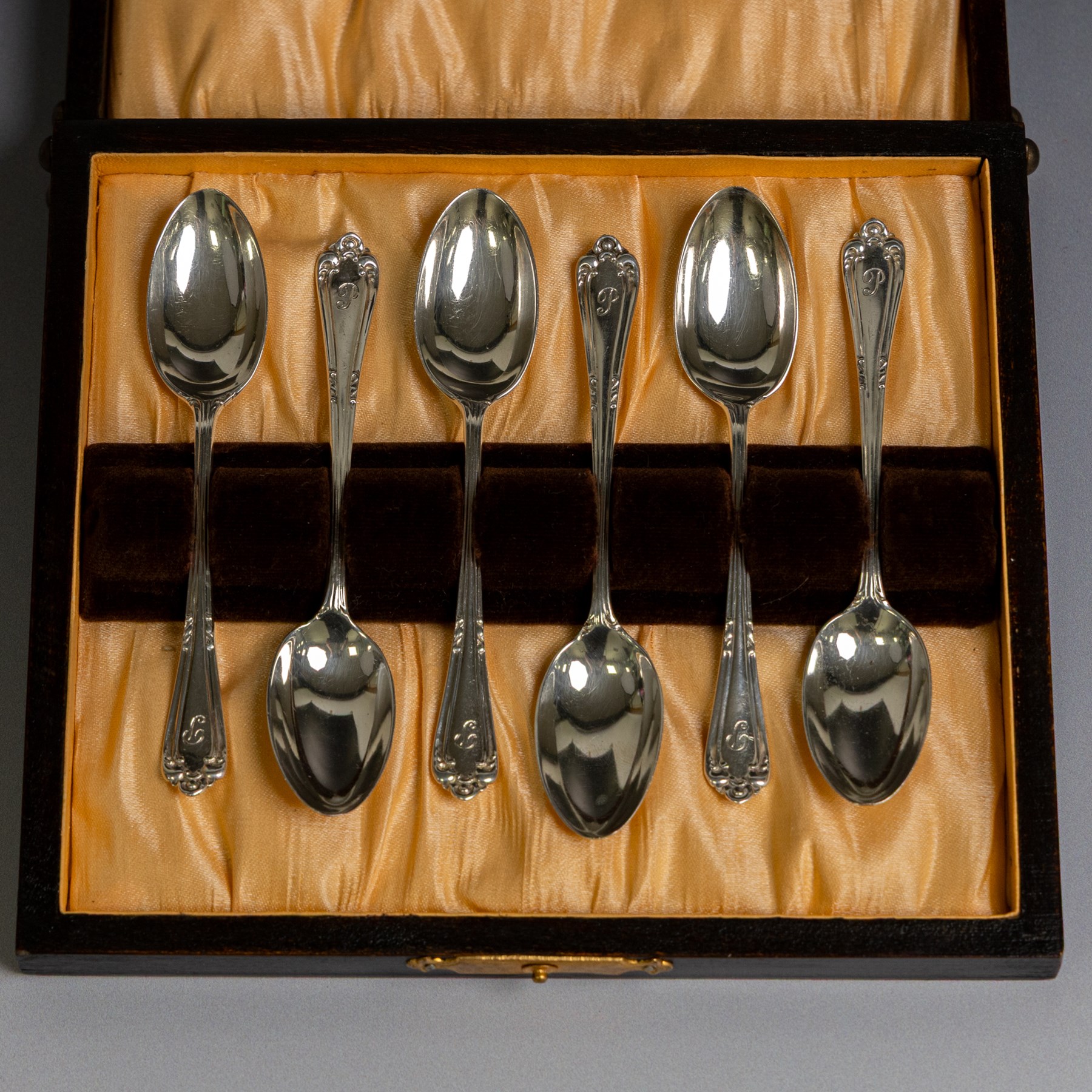 Two sets of early 20th century cased silver coffee spoons, comprising a set of six with scrolling decoration and engraved initials and a set of six coffee bean spoons, all hallmarked 