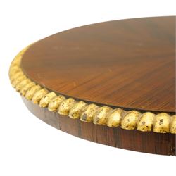 French Empire design rosewood and parcel-gilt occasional table, the circular top with sunburst veneer and giltwood gadrooned edge, raised on a turned and lobed pedestal terminating to a triform platform base with gilt beading, raised on three large paw feet with scrolling foliate brackets
