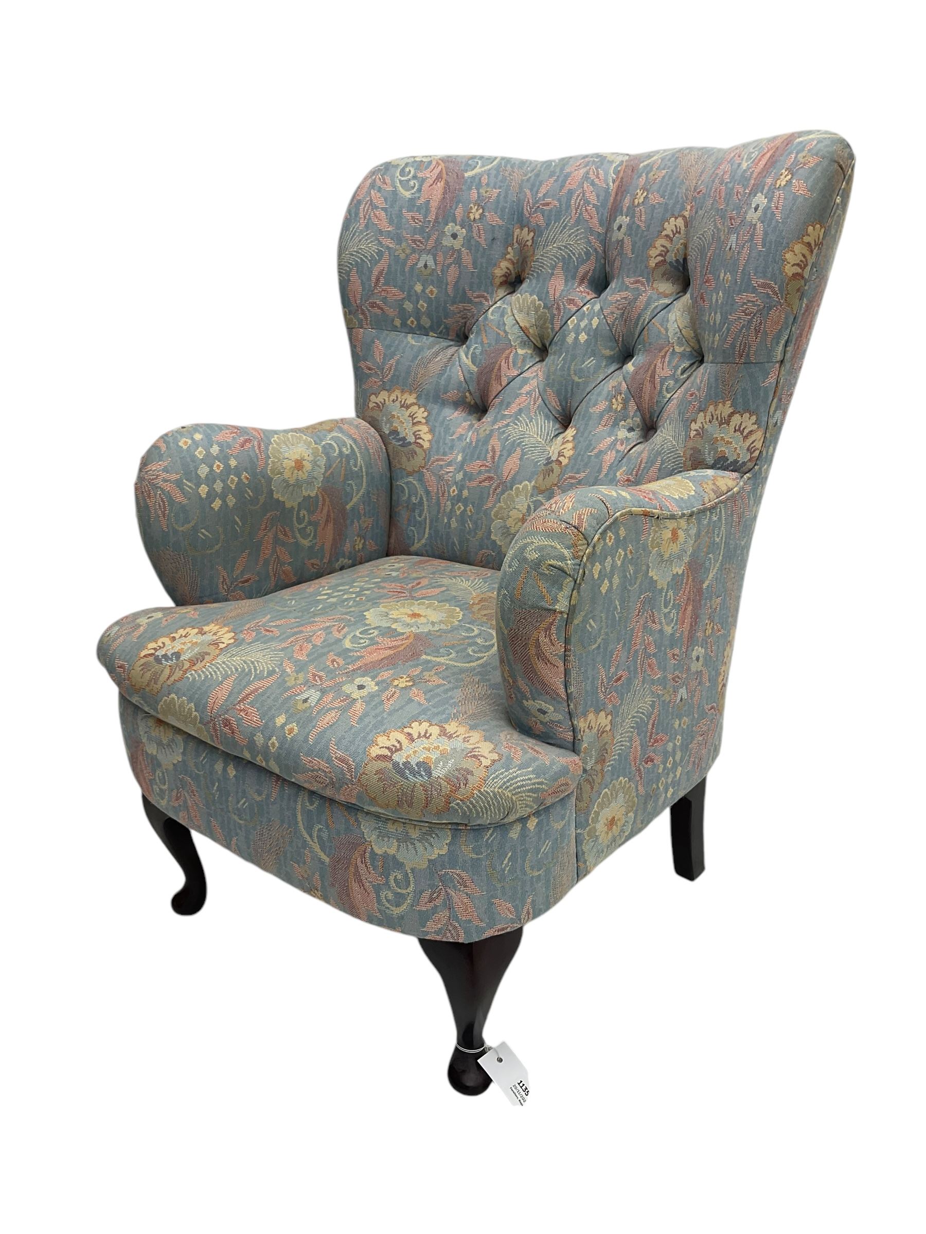 Mid-20th century wingback armchair, upholstered in soft blue floral patterned fabric with button-tufted backrest and curved arms and raised on cabriole supports