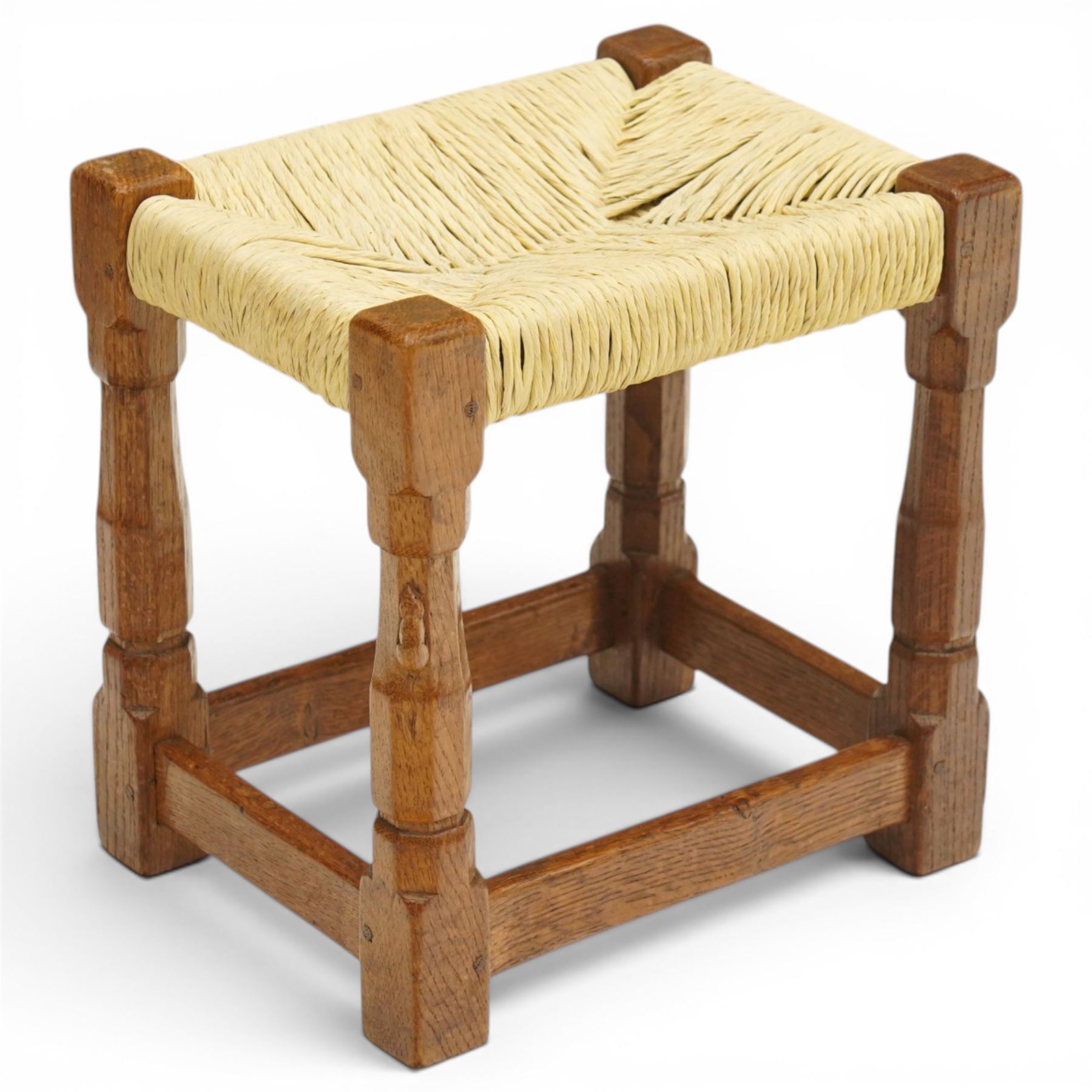Mouseman - mid-20th century oak stool, the rectangular rush seat raised on turned octagonal supports united by box stretcher, with carved mouse signature, by the workshop of Robert Thompson of Kilburn