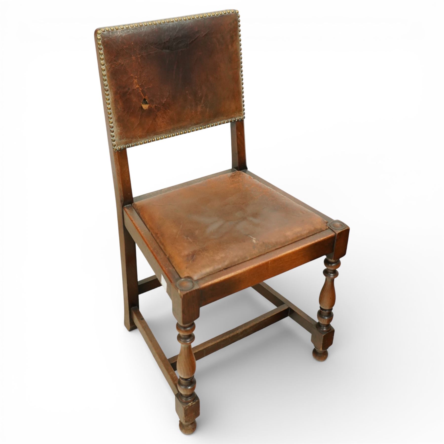 Early 20th century four oak side chairs, with studded leather upholstered backs and seats, on square section legs with baluster turned front supports and straight stretchers